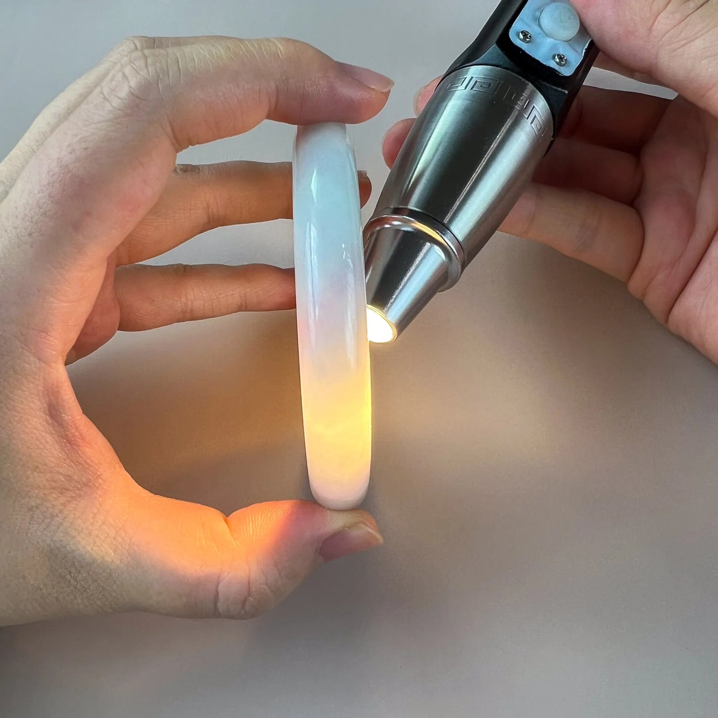 Side profile of translucent jade bangle lit from behind to show color and clarity