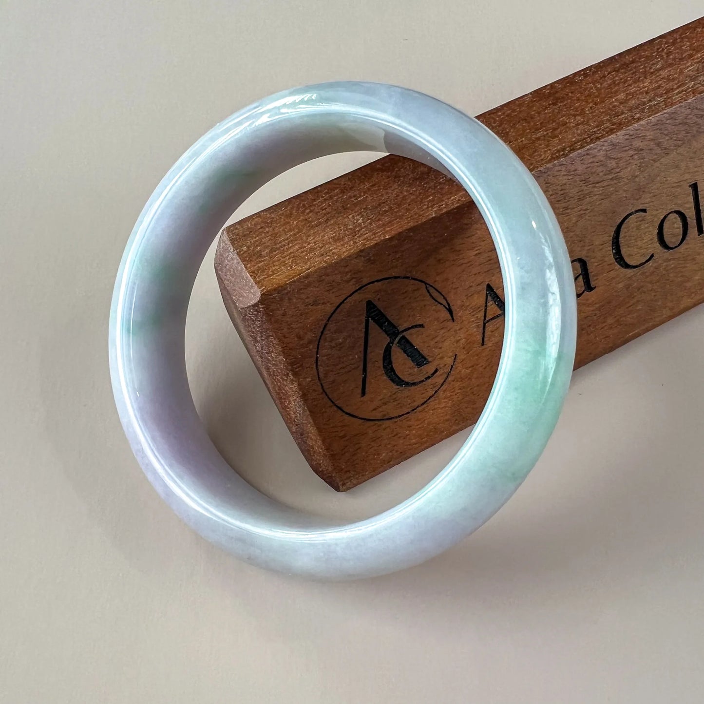 Glossy pale blue jade bangle front view on display stand with soft green marbling