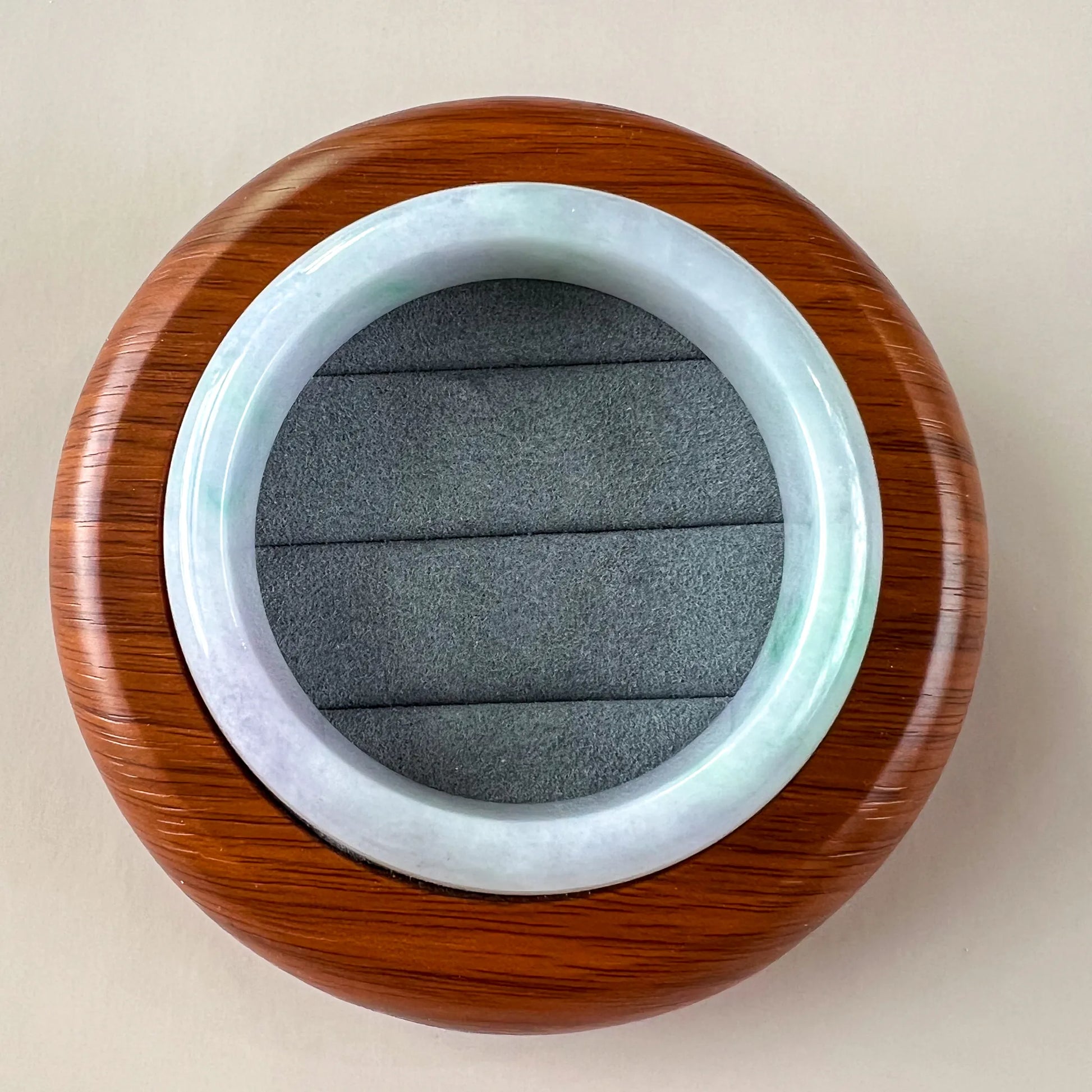 Top view of polished jade bangle in wooden presentation case with gray insert