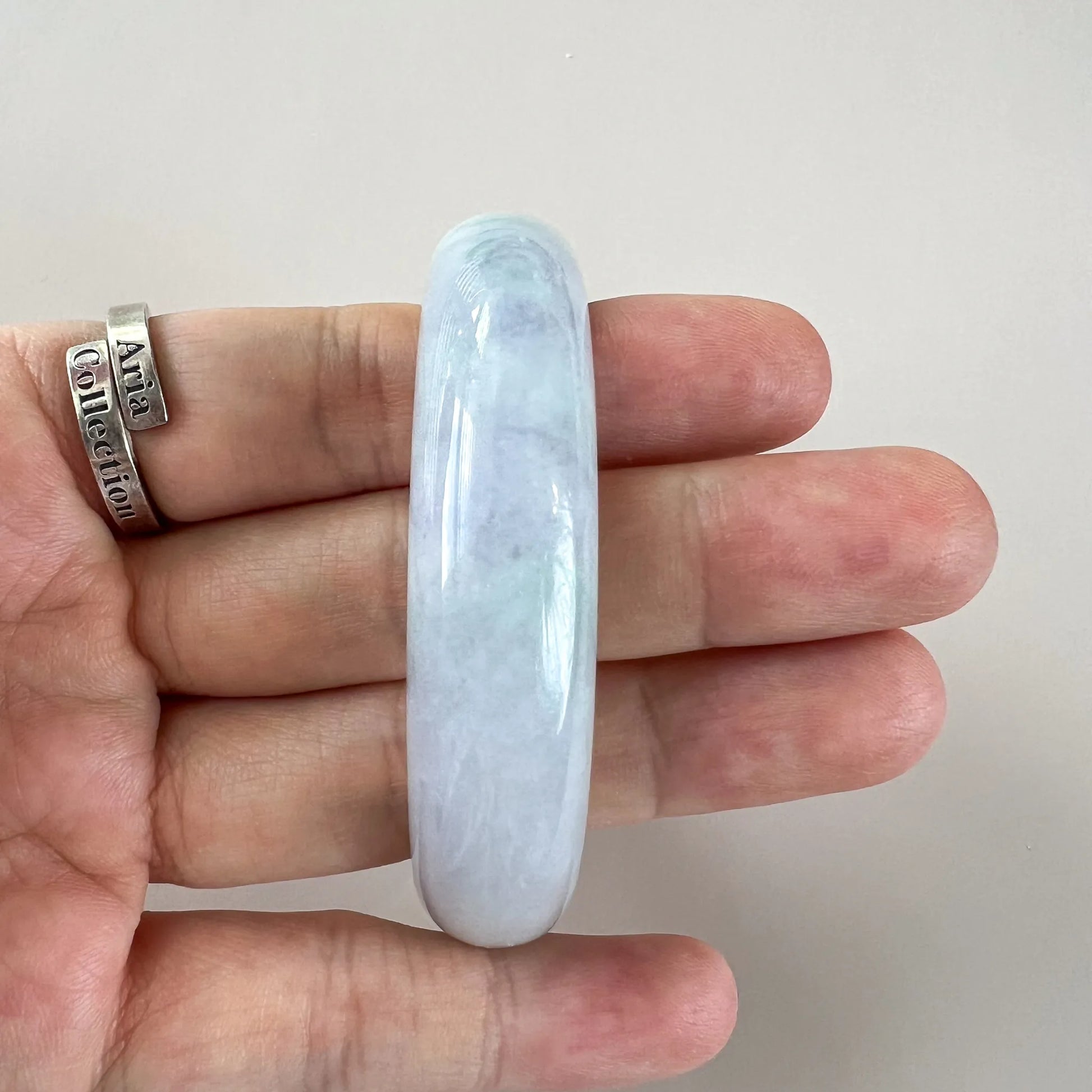 Side view of glossy jade bangle on hand, showing smooth curved profile