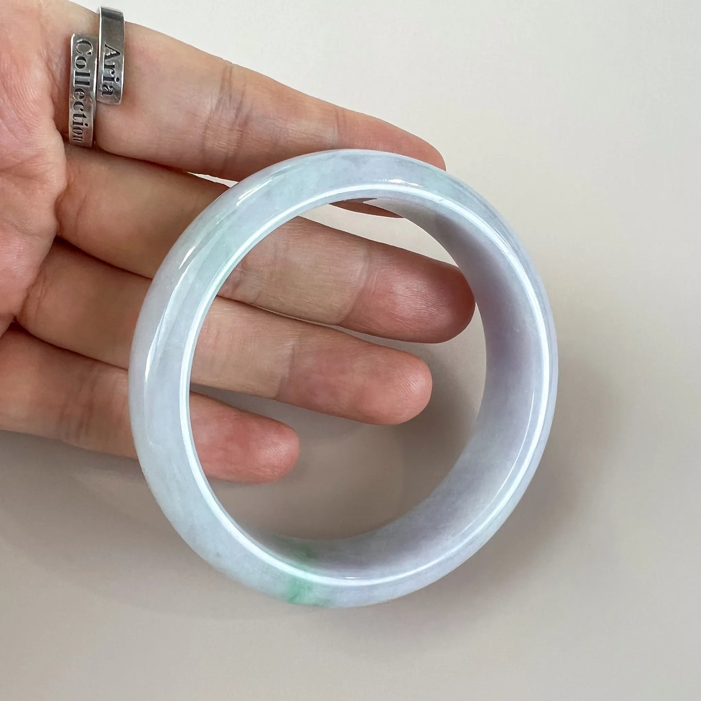 Open circular view of pale jade bangle held in hand, polished and translucent