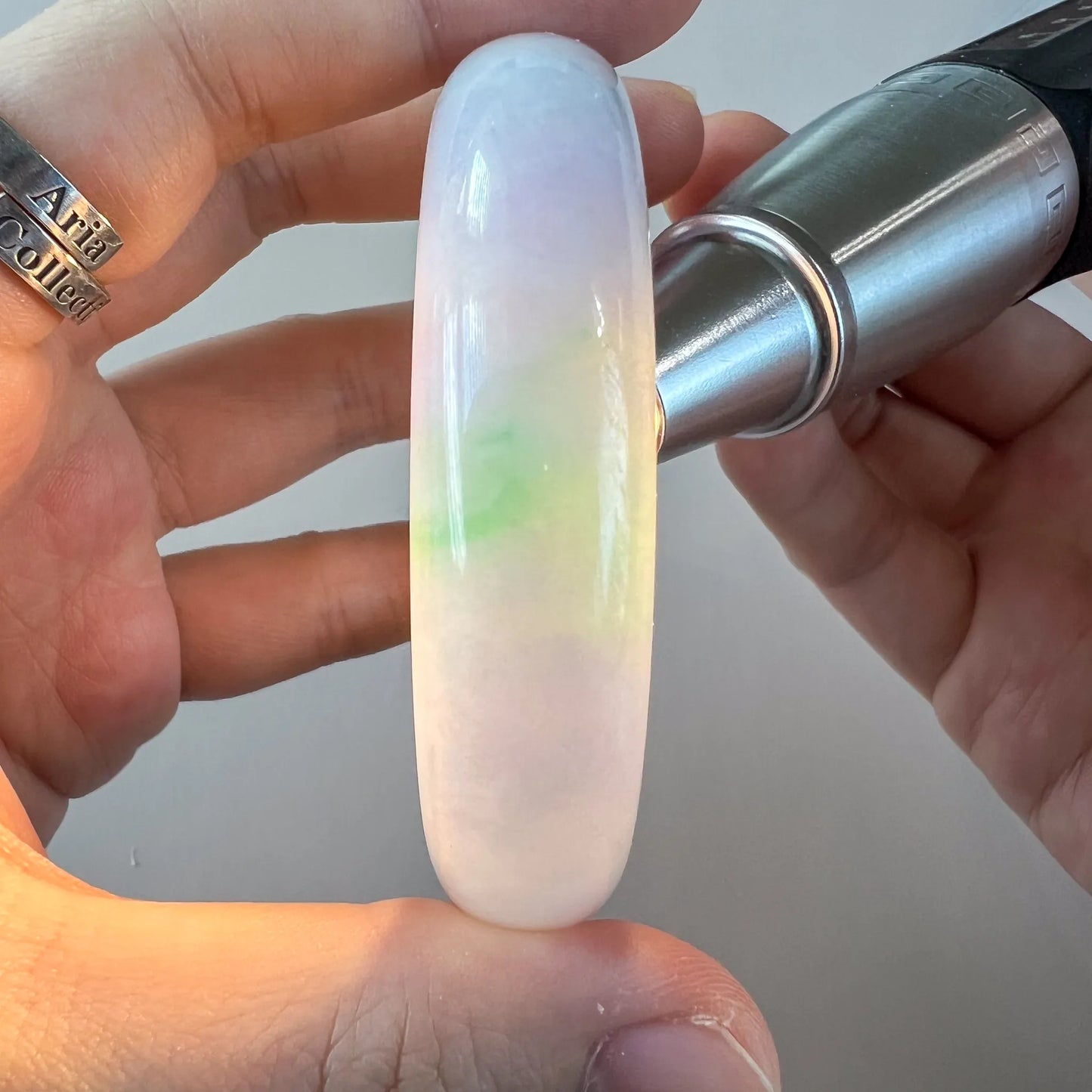 Vertical side view of smooth jade bangle with milky lavender and green glow