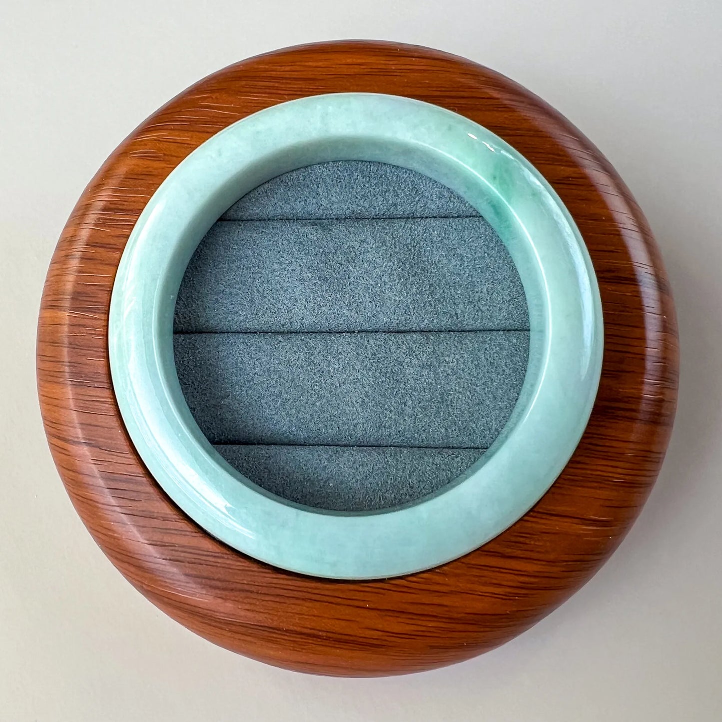 Top view of polished aqua jade bangle in a wooden display box with padded insert