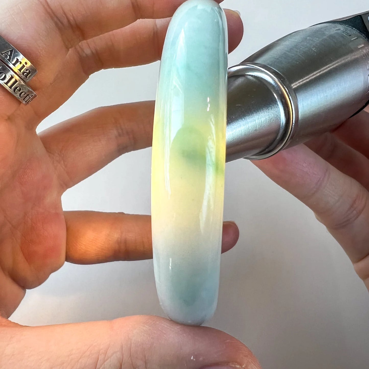 Side view of translucent blue green jade bangle with light passing through the stone