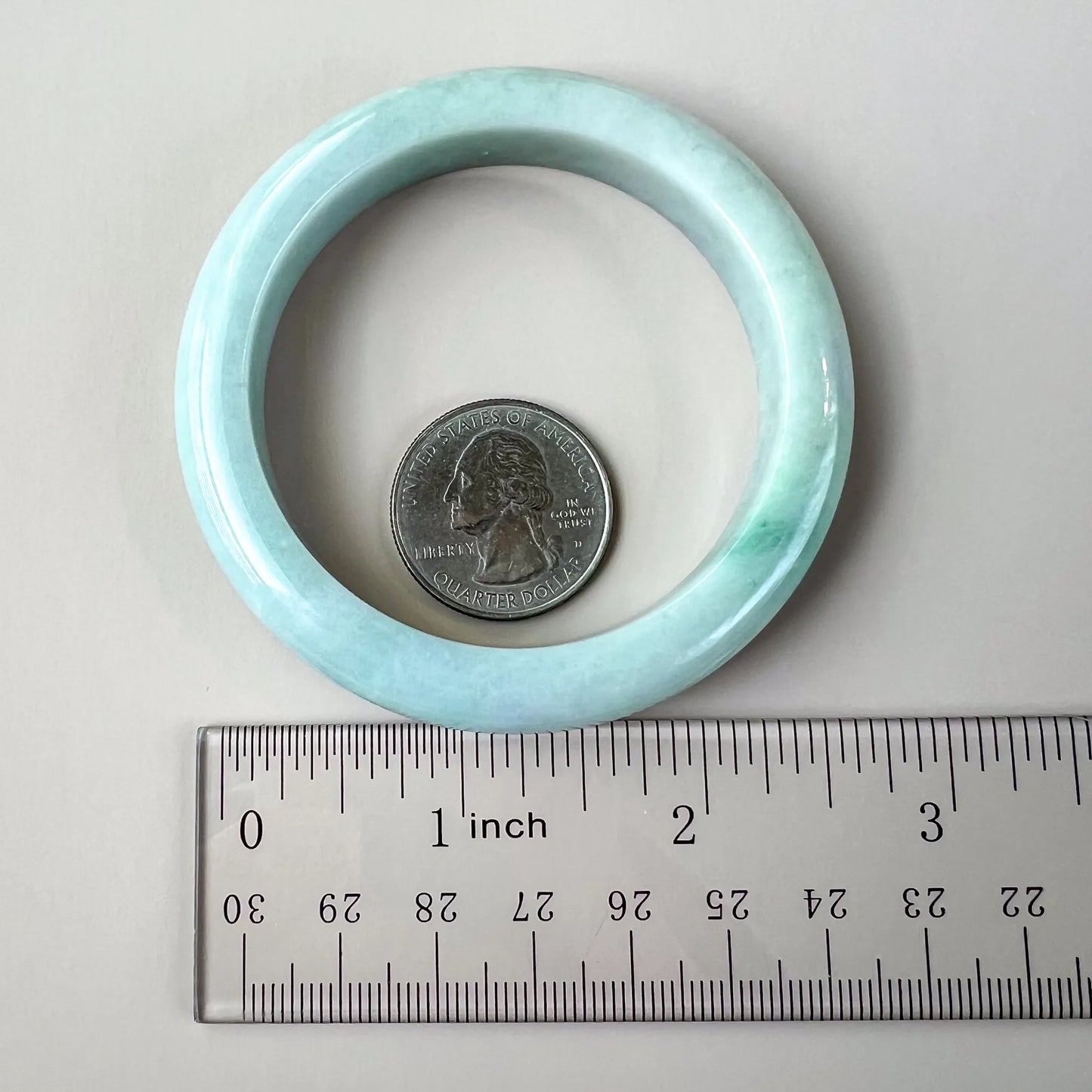 Light blue bangle shown with ruler and quarter, rounded profile and polished inner surface