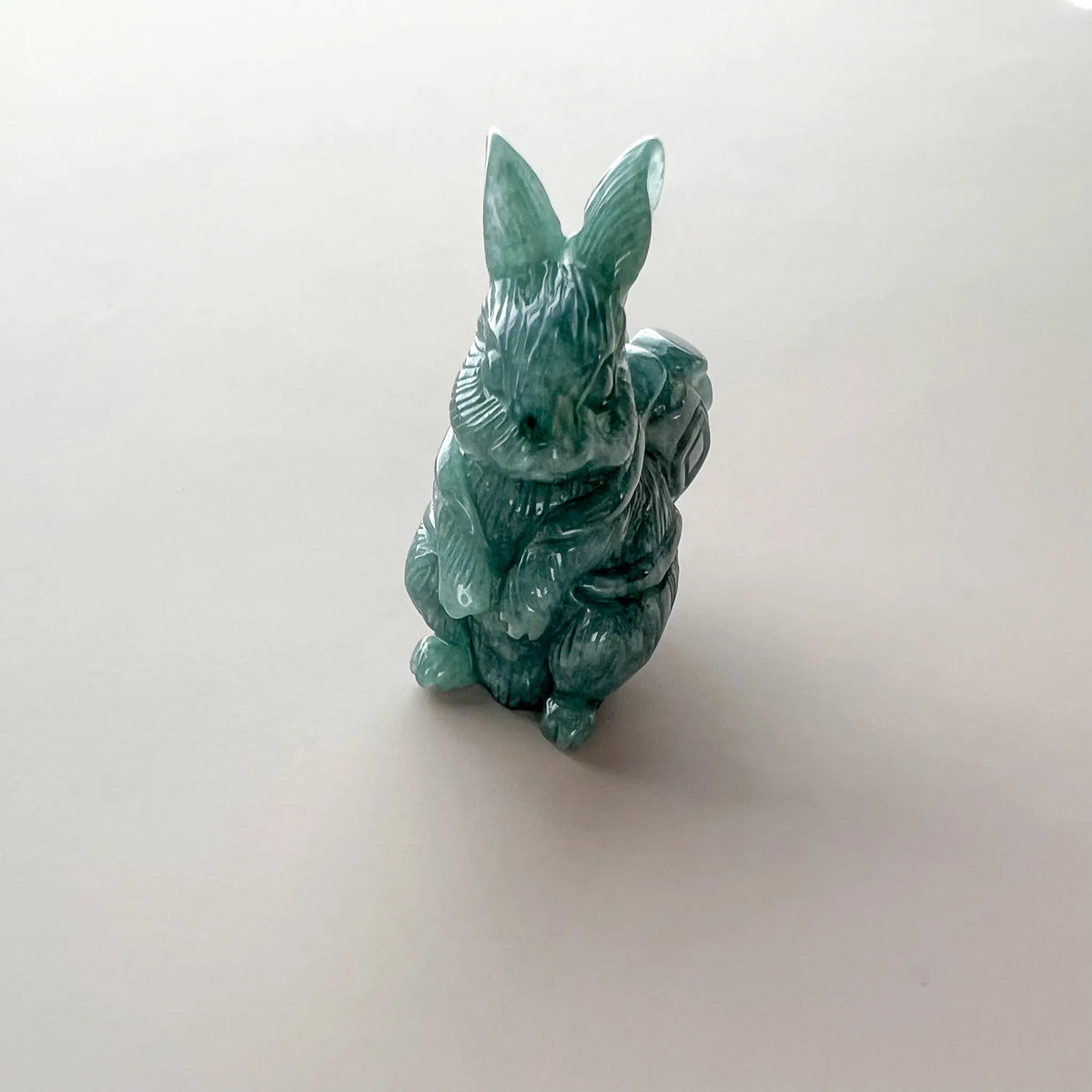 Front angle of polished green natural jade rabbit showing upright ears, paws, and carved basket