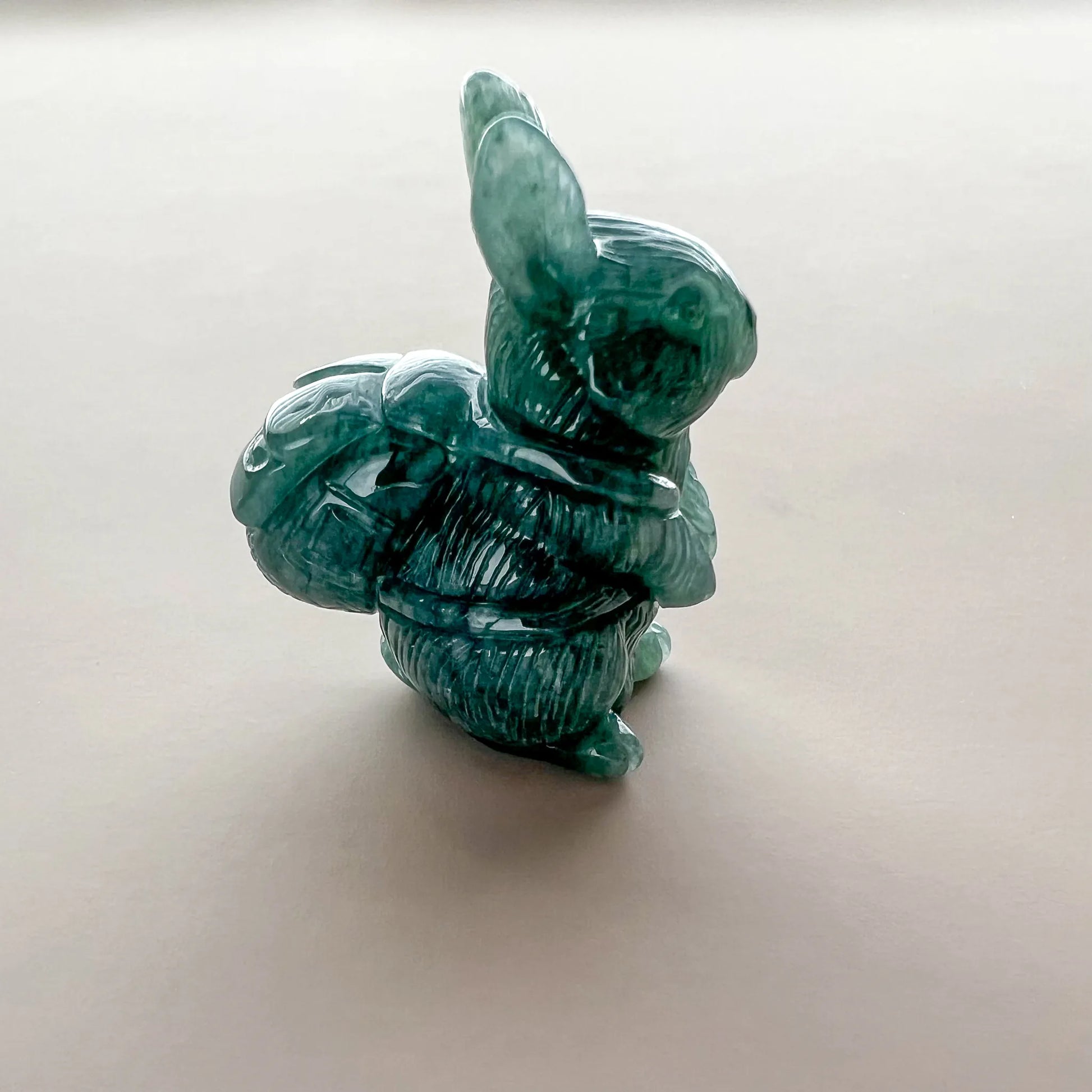 Rear three-quarter view of green carved stone rabbit sculpture with polished finish