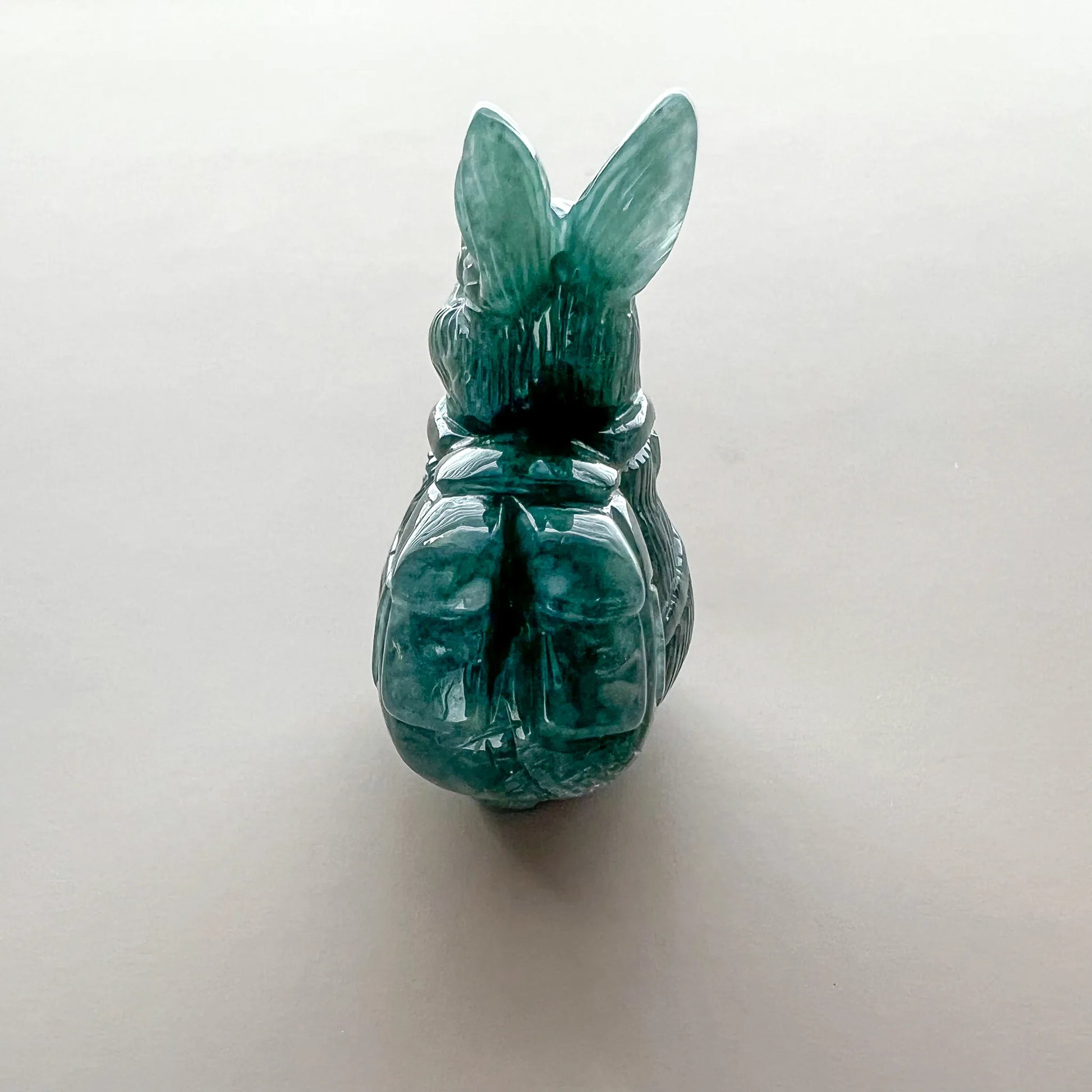Back view of translucent green carved rabbit figurine with glossy polished stone finish