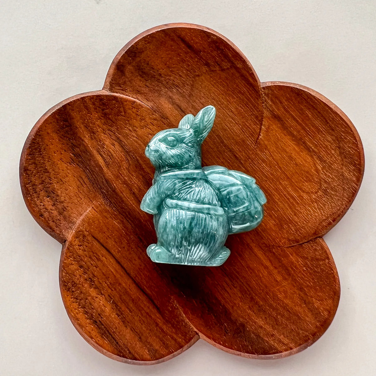 Top-down view of green stone rabbit sculpture on flower-shaped wooden base