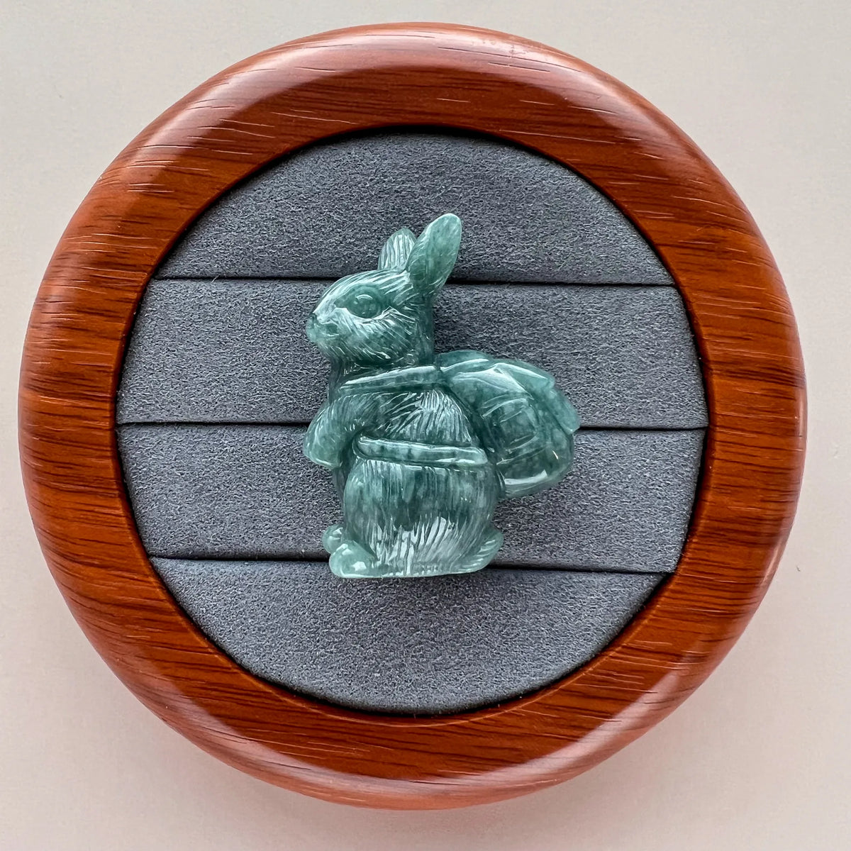 Green stone rabbit sculpture in round presentation case with gray padded insert