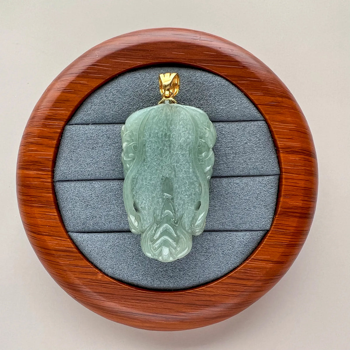 Back view of light green Natural Jade pendant showing shallow carving and a polished gold-tone bail