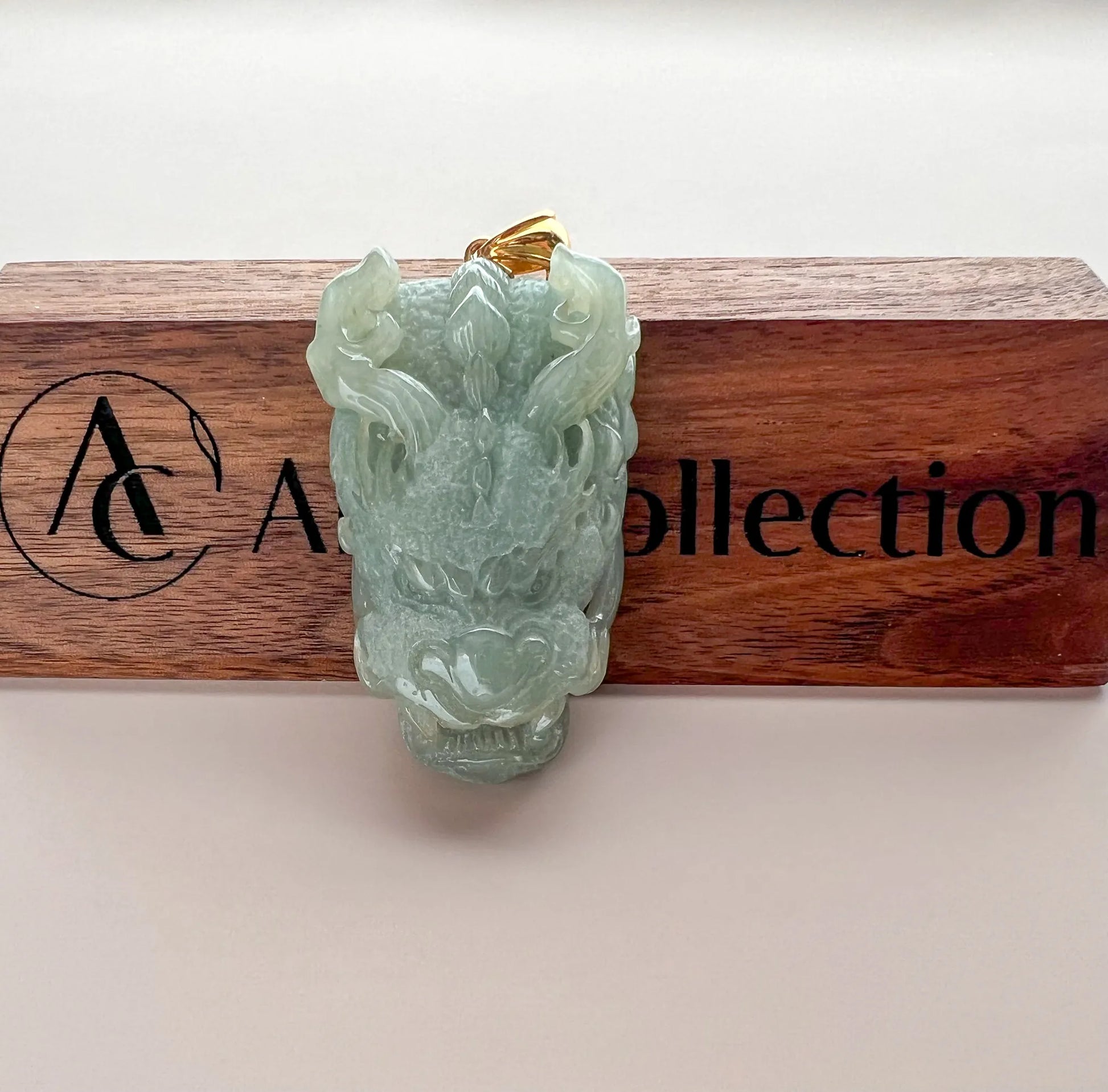 Front view of green jade dragon pendant displayed on branded wooden holder