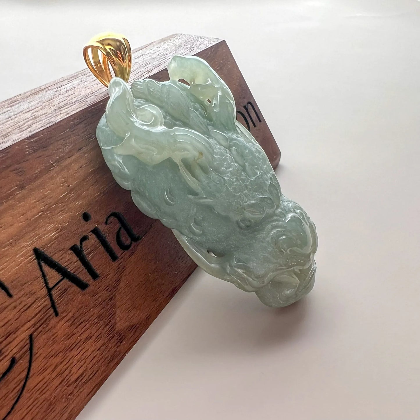 Angled side view of translucent green jade pendant with sculpted dragon details