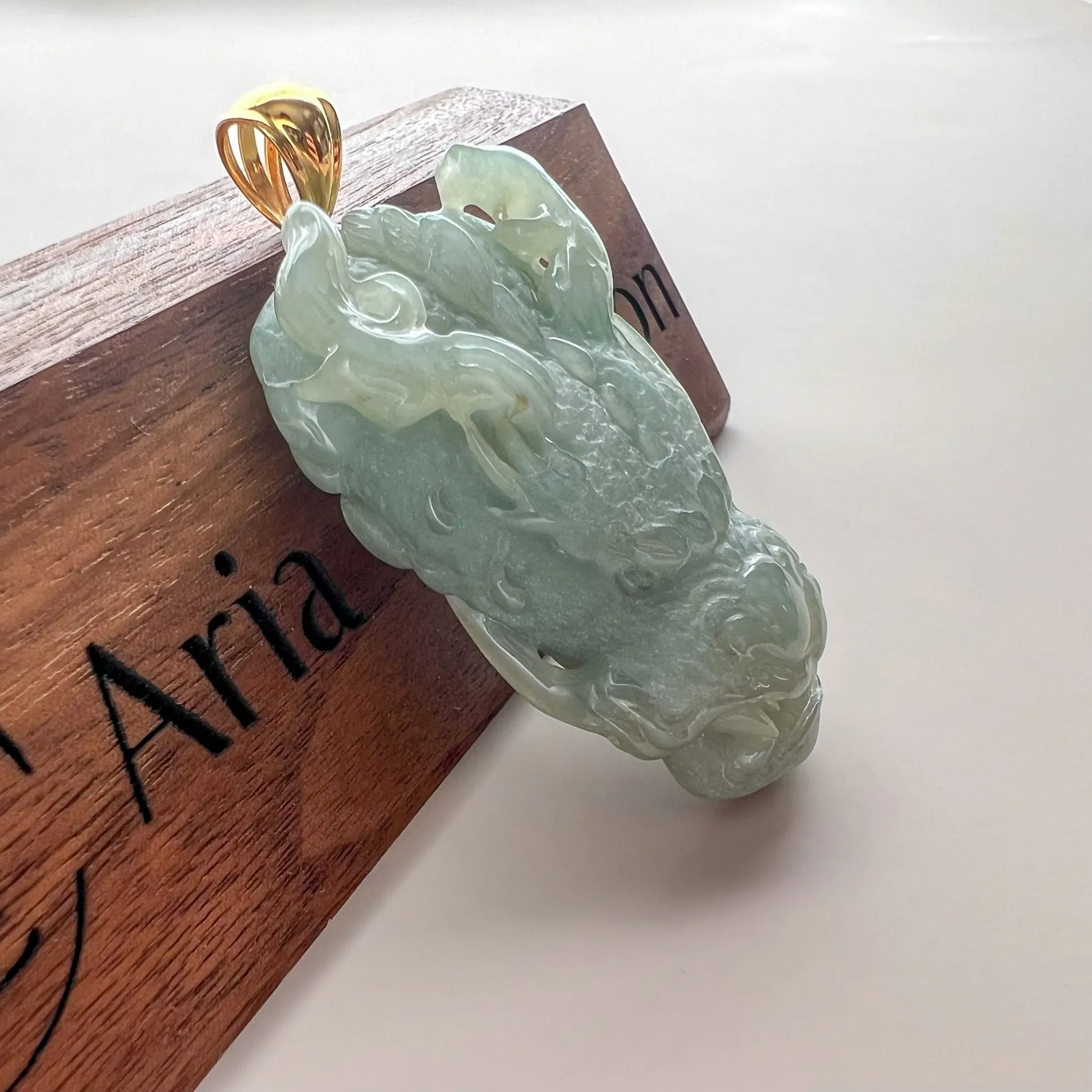 Angled side view of translucent green jade pendant with sculpted dragon details