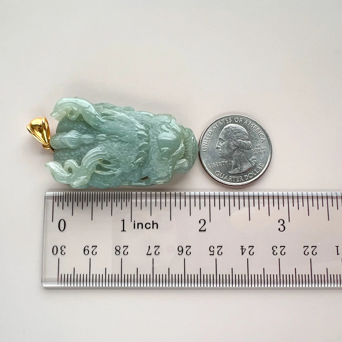 Side view of jade pendant with ruler and quarter for size reference