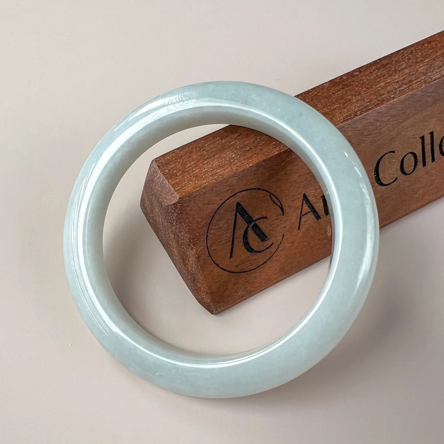 Front view of glossy pale blue jade bangle on neutral background