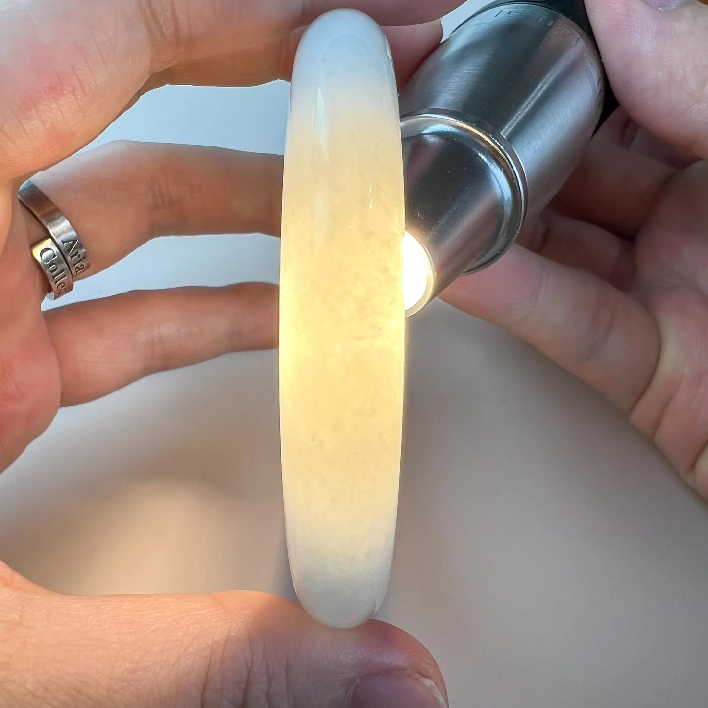 Translucent jade bangle backlit to show warm honey tones