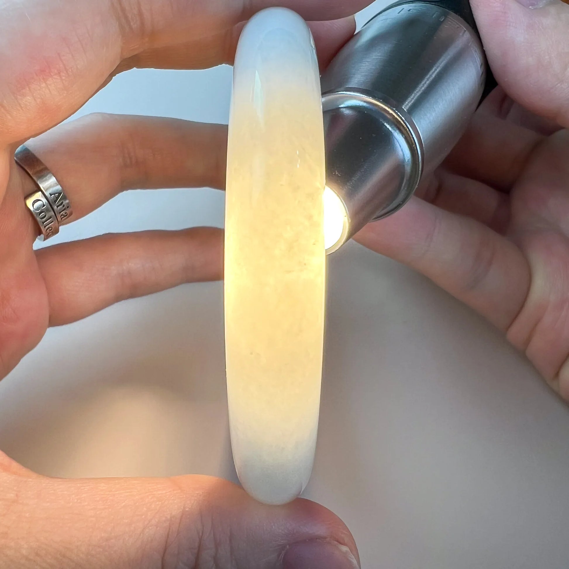 Translucent jade bangle backlit to show warm honey tones