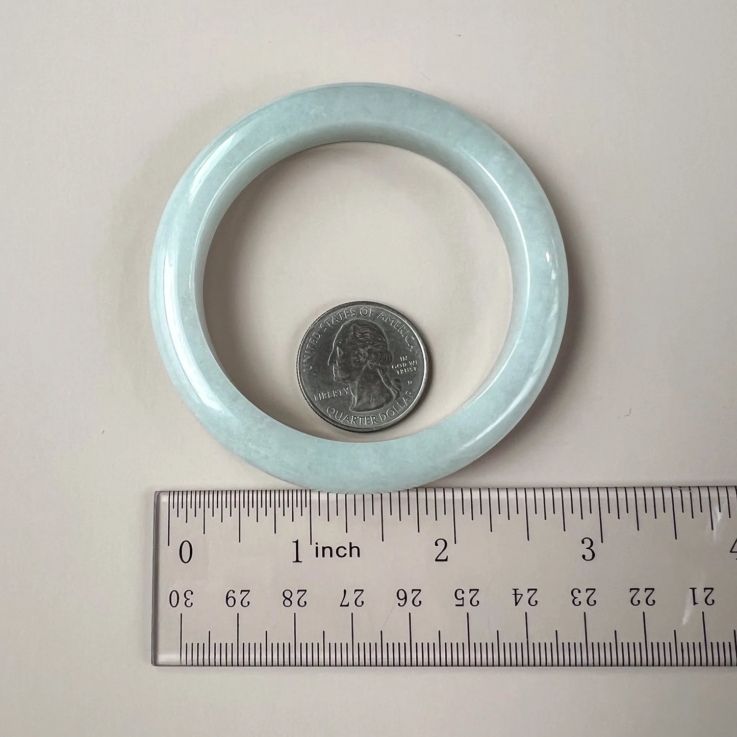 Jade bangle shown with quarter and ruler for size reference