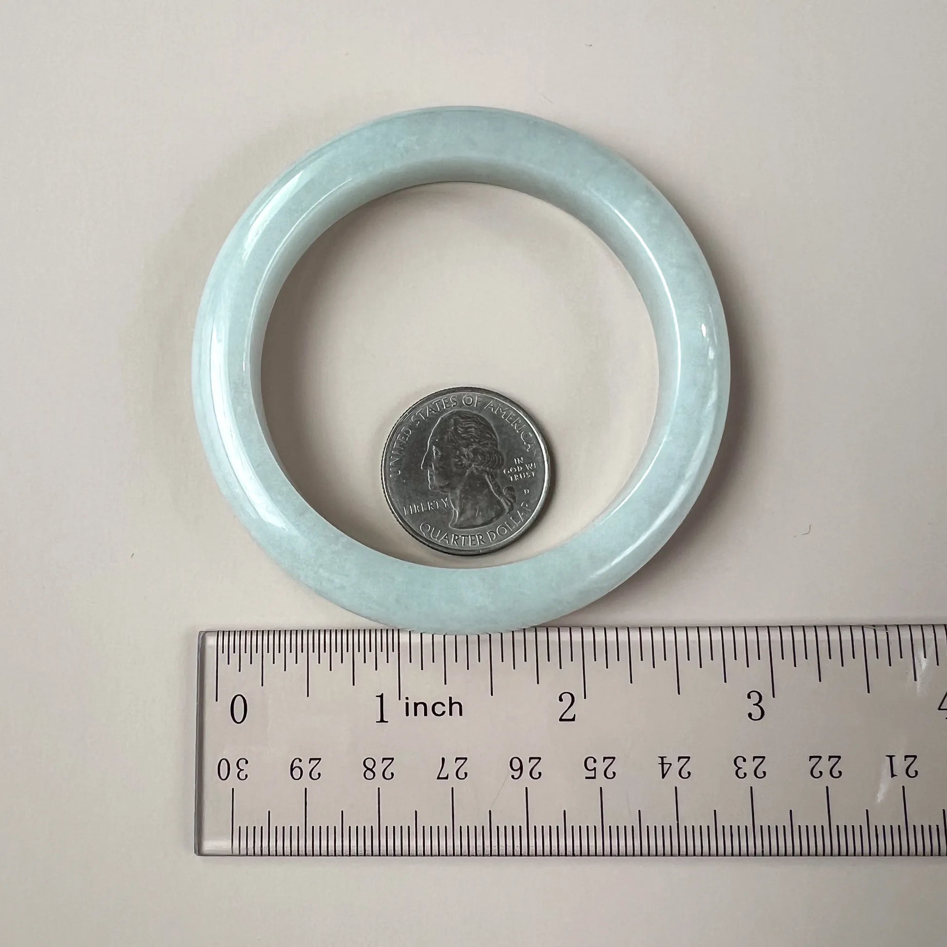 Jade bangle shown with quarter and ruler for size reference