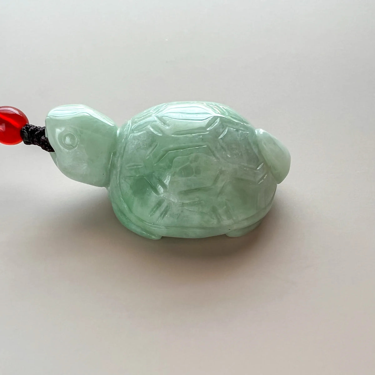 Opposite side view of green jade turtle pendant showing smooth carved head and shell