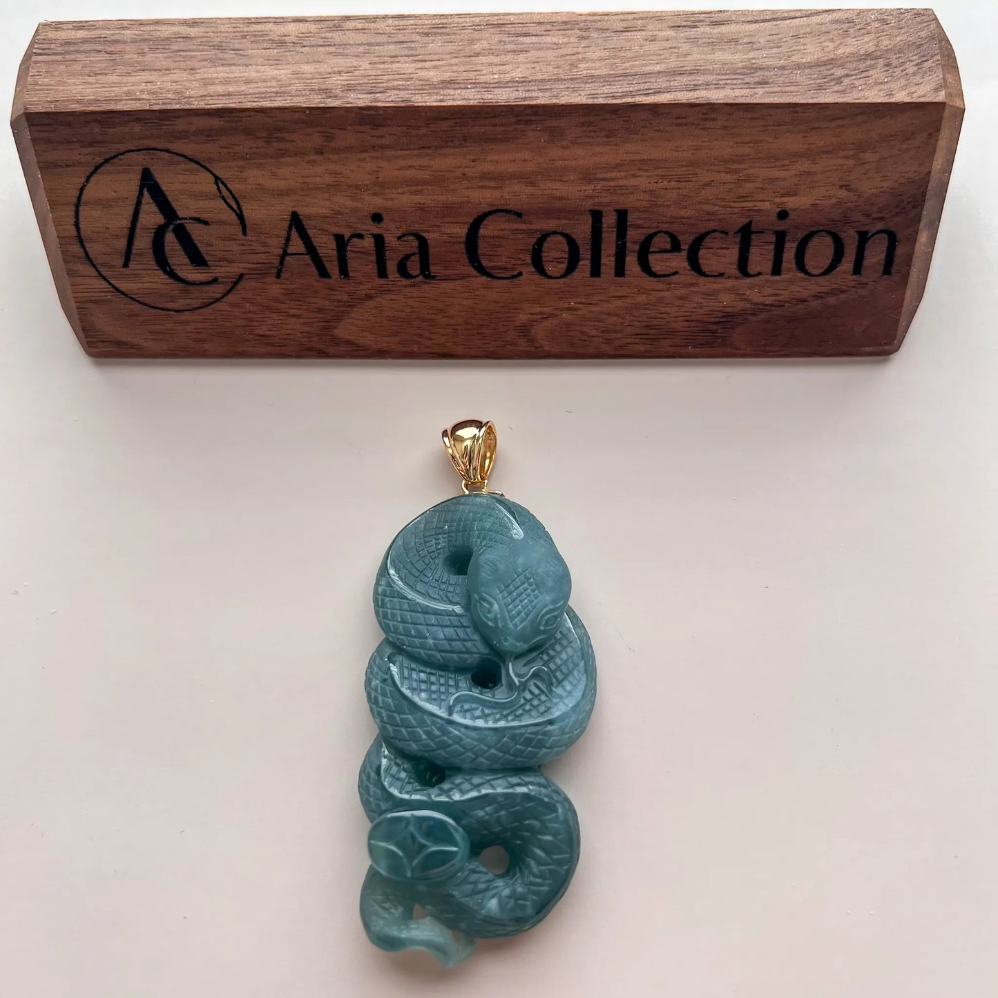 Pendant shown below Aria Collection plaque on white background for scale