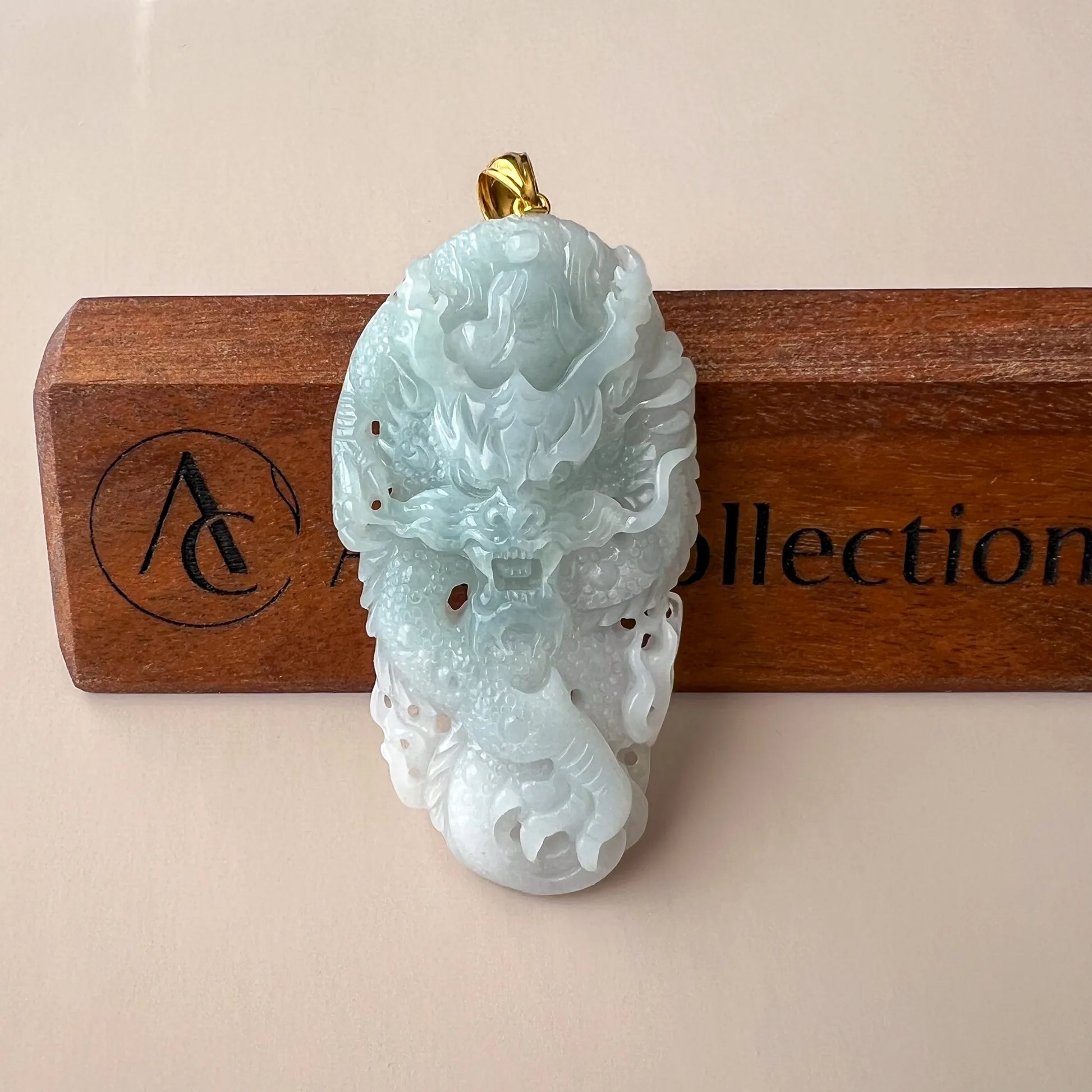 Front view of pale blue carved jade pendant on a wooden display stand