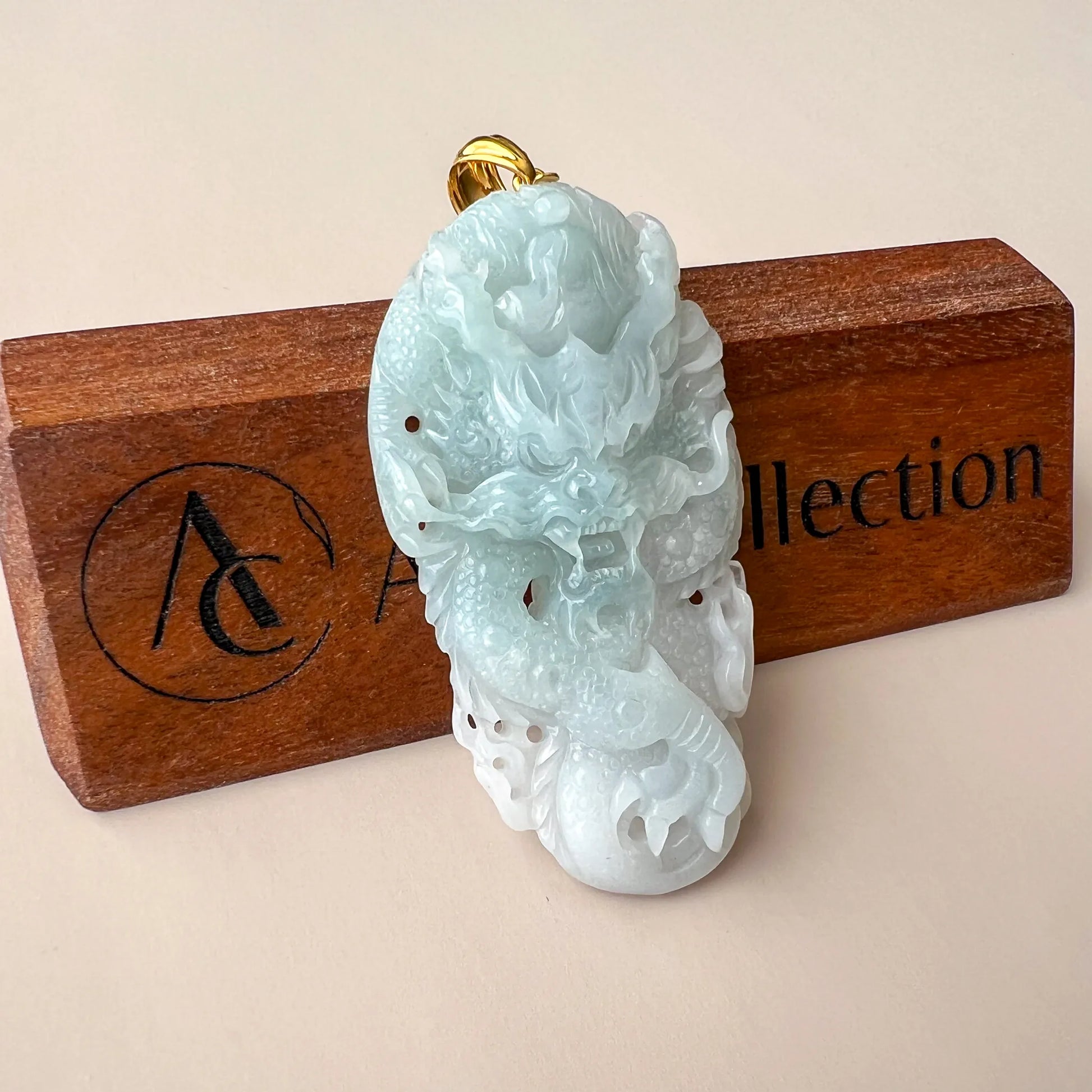 Front angled view of icy jade carving pendant with detailed relief and gold bail