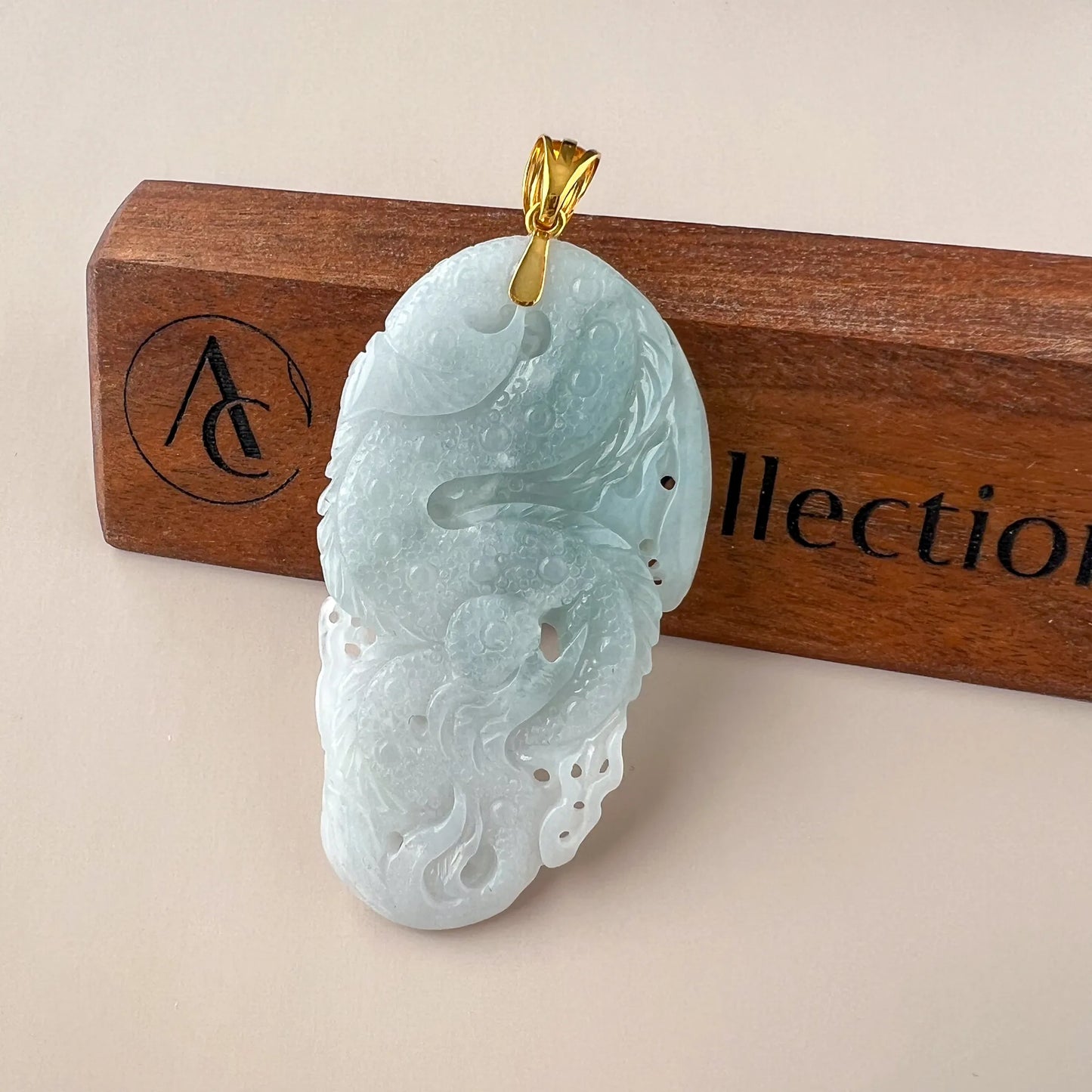 Back view of carved pale jade pendant showing polished stone surface and gold bail