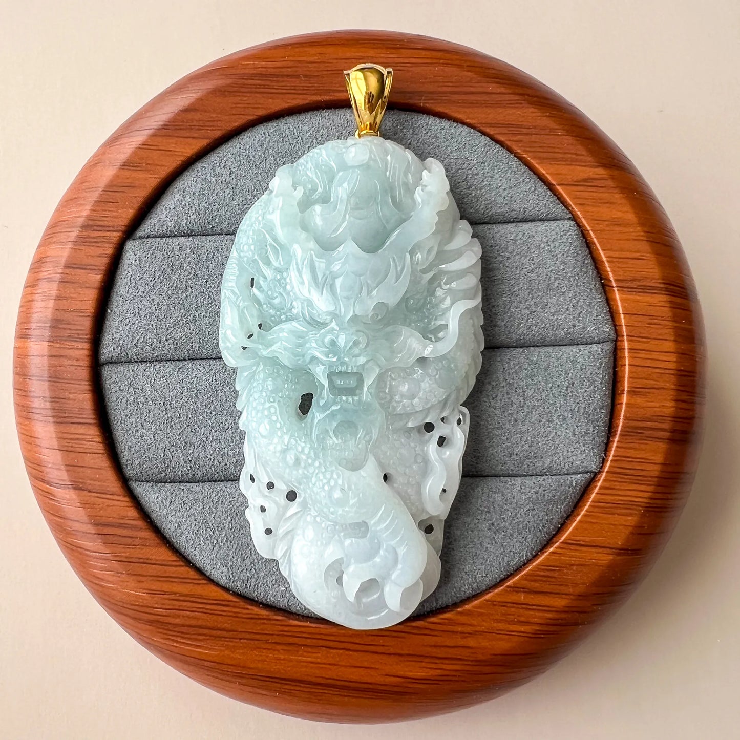 Front view of jade pendant in round presentation box with padded gray insert
