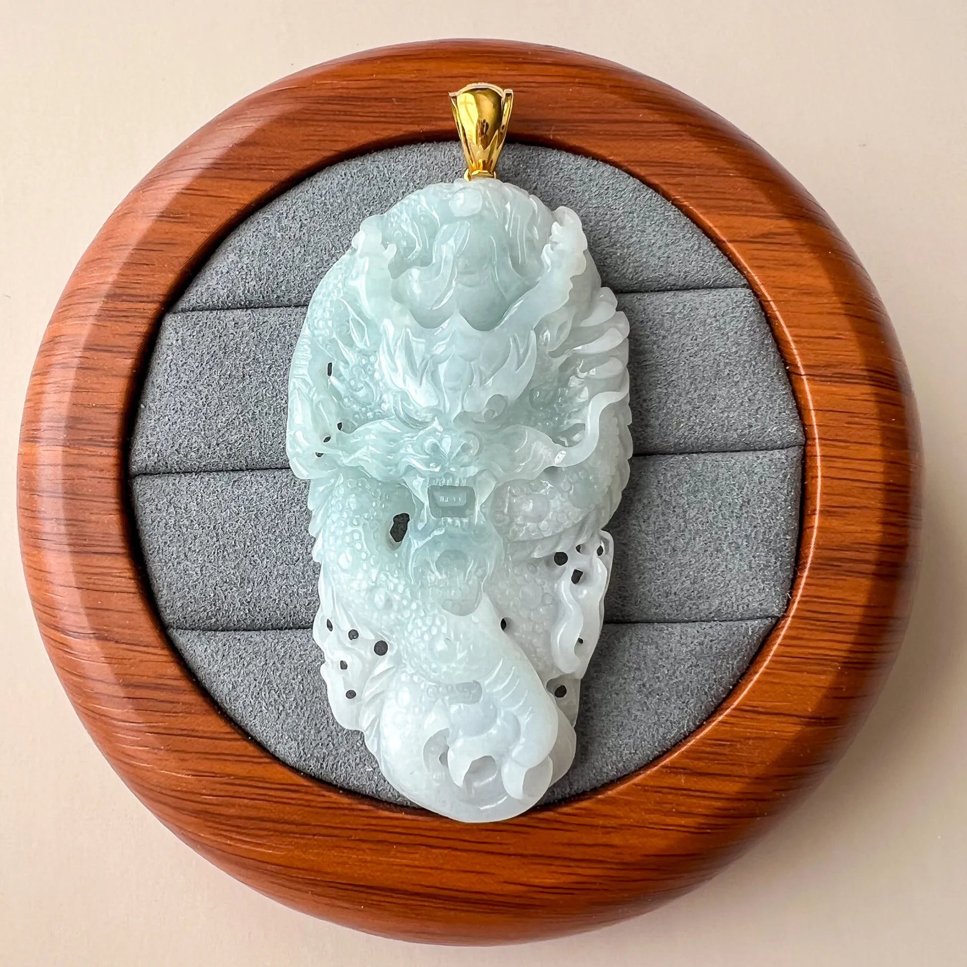 Front view of jade pendant in round presentation box with padded gray insert