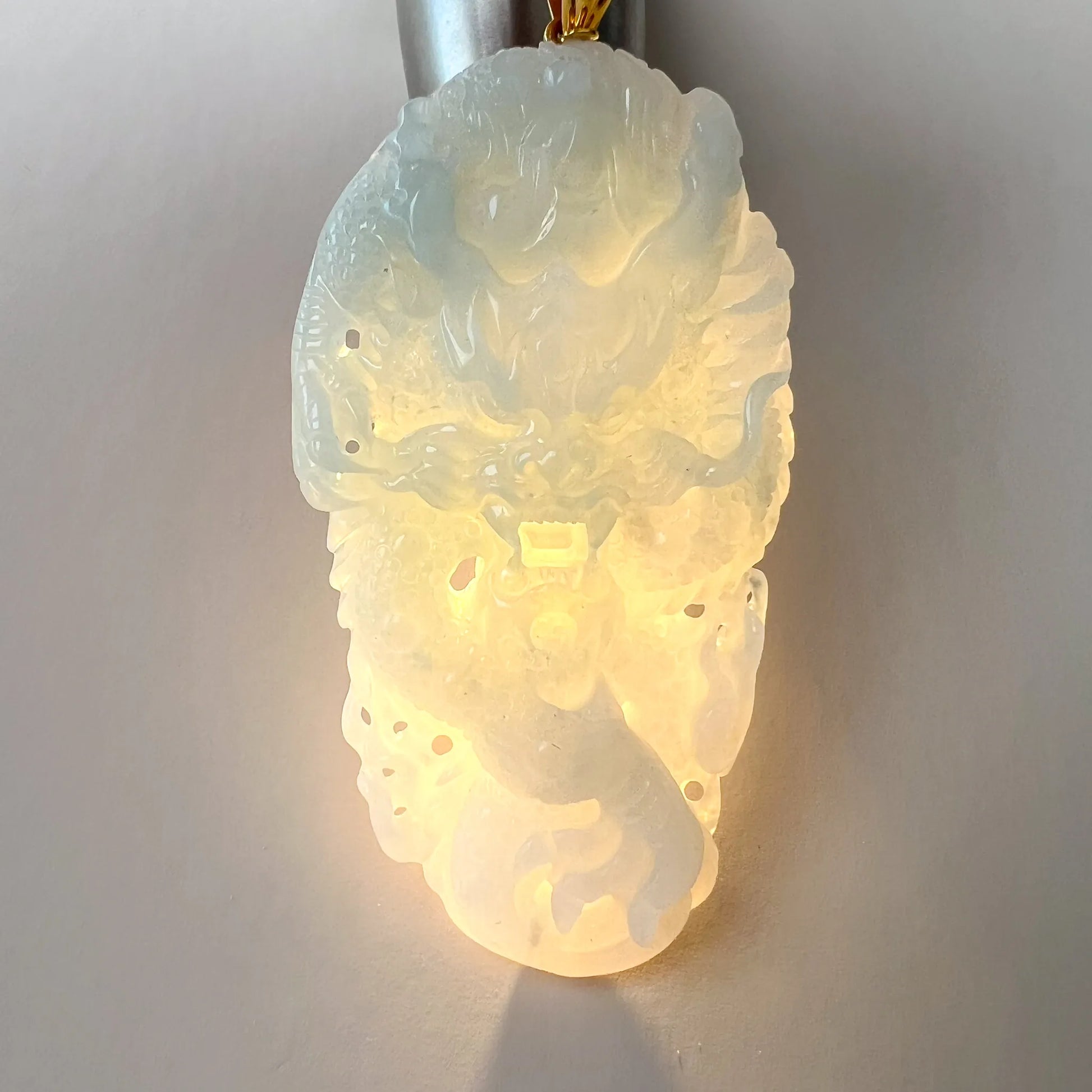 Backlit view of translucent jade pendant showing glow through the carved stone