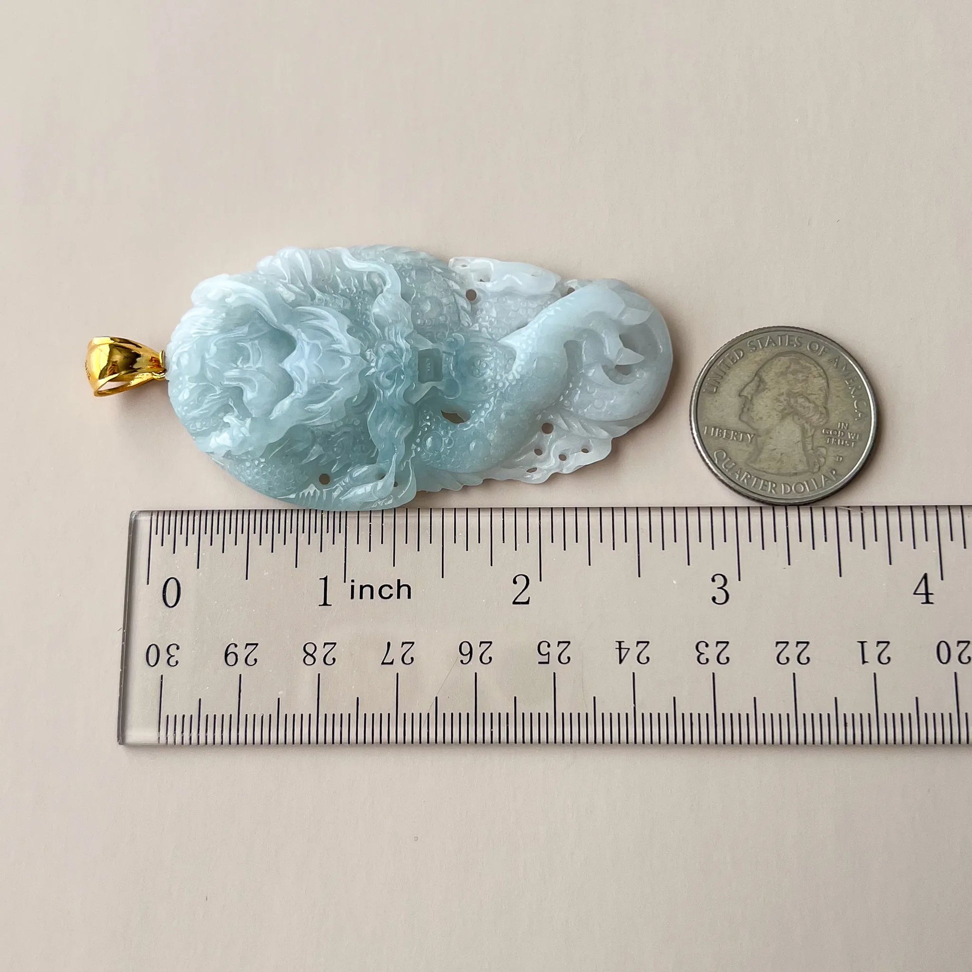 Side view of icy blue Natural Jade dragon pendant with gold-tone bail, ruler and coin for scale