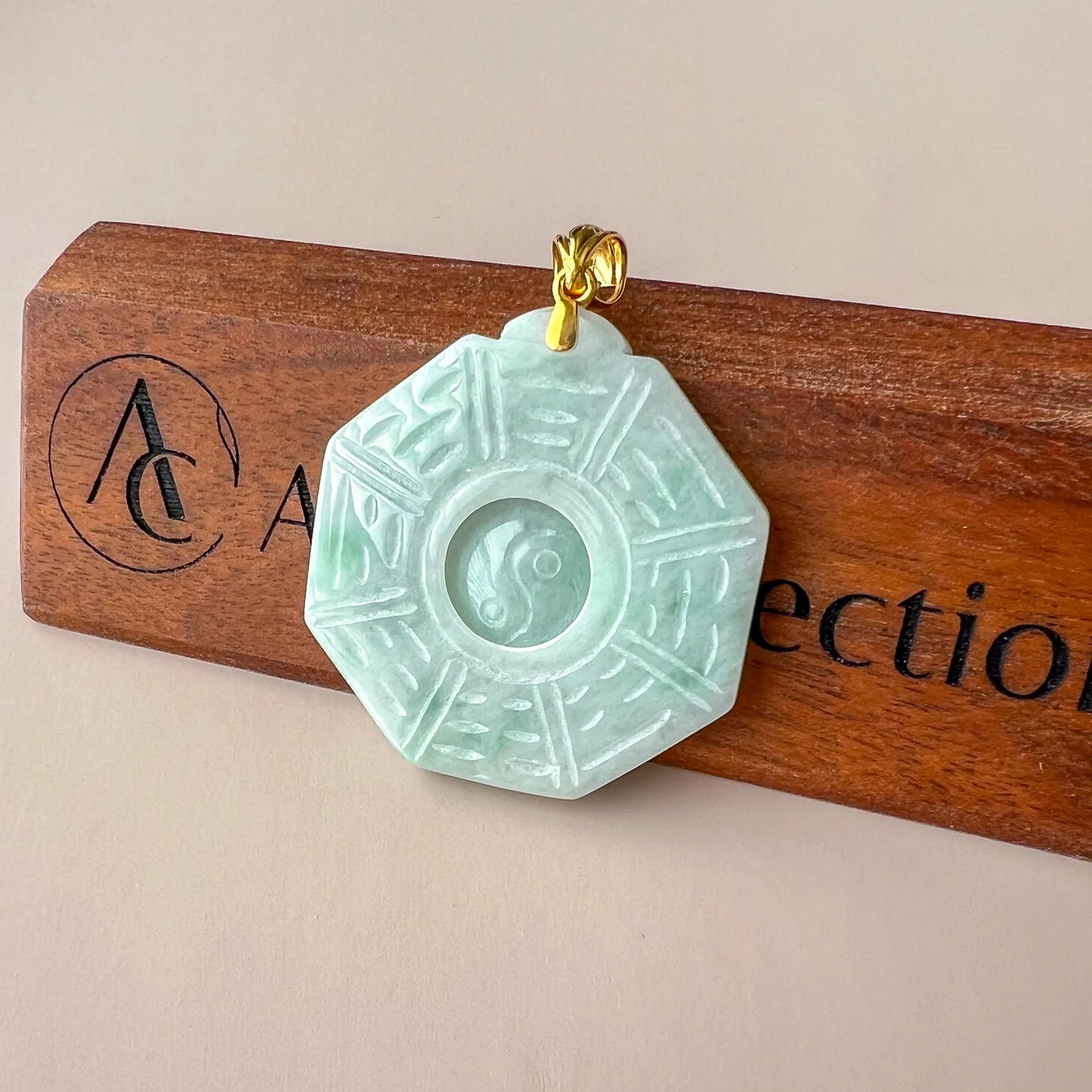 Angled view of octagonal jade pendant showing carved yin yang center and gold bail