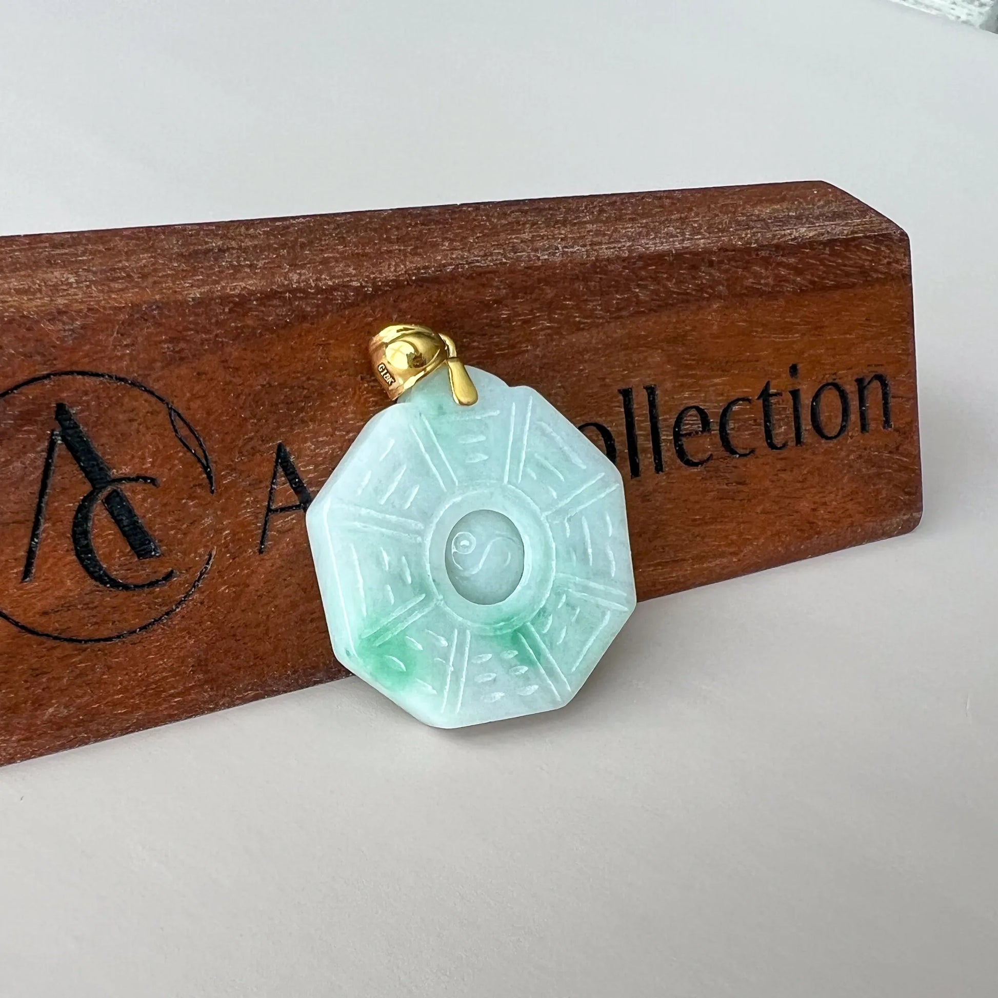 Front view of translucent jade pendant with octagonal carving on wooden display