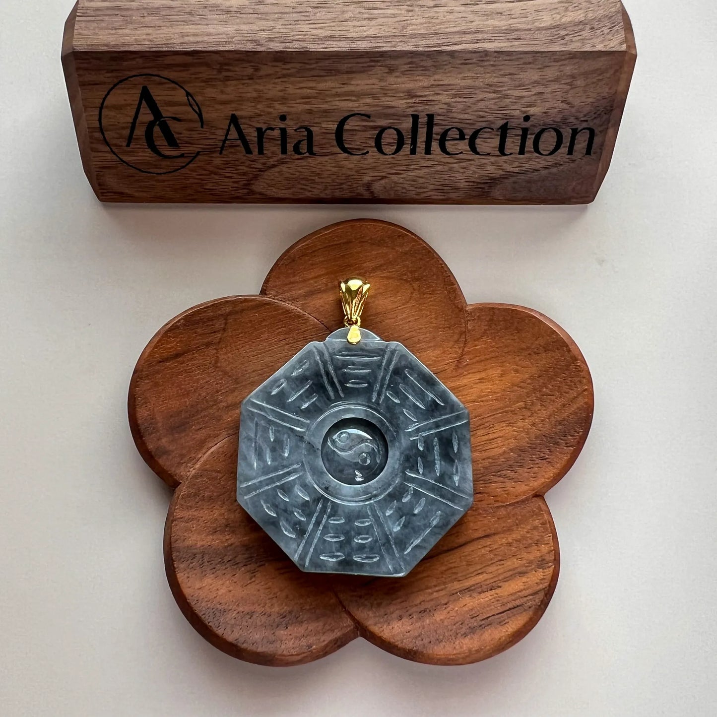 Octagonal carved jade pendant on flower-shaped wooden display base, front view