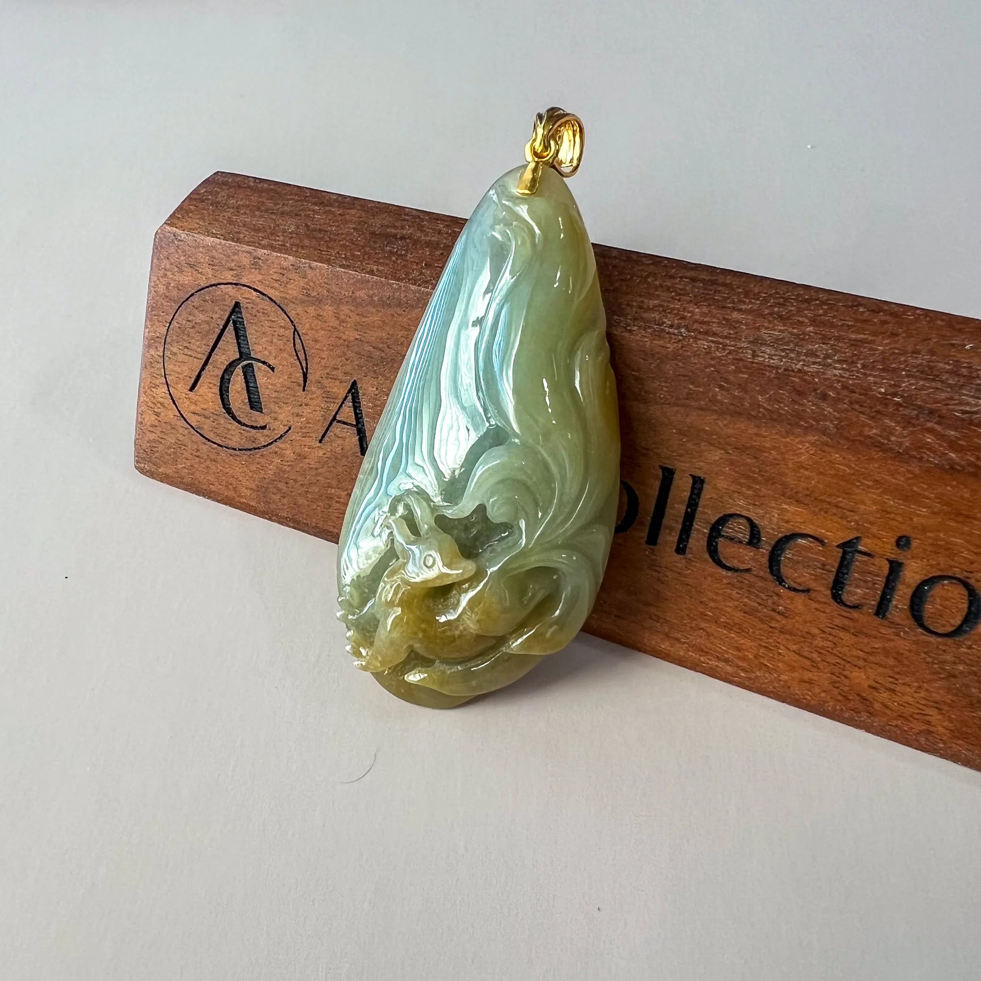 Angled front view of carved jade pendant showing glossy surface and gold bail