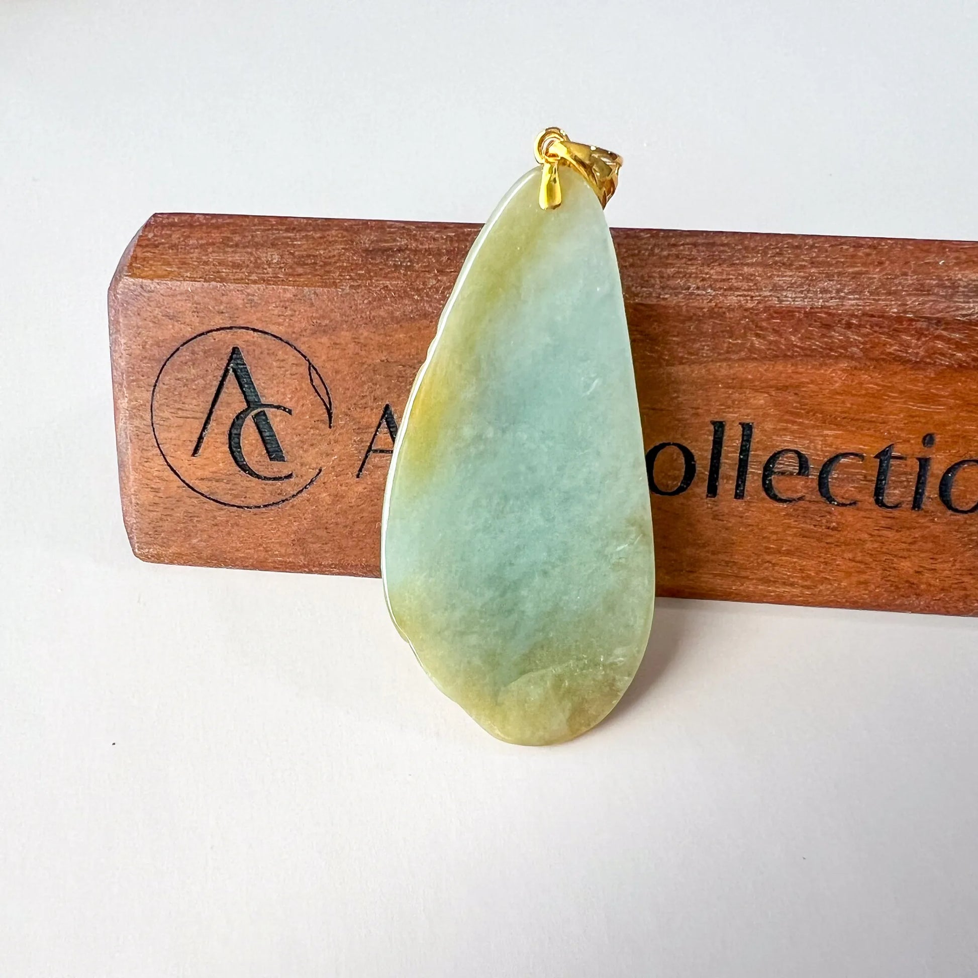 Back view of teardrop jade pendant with smooth polished green stone and gold bail