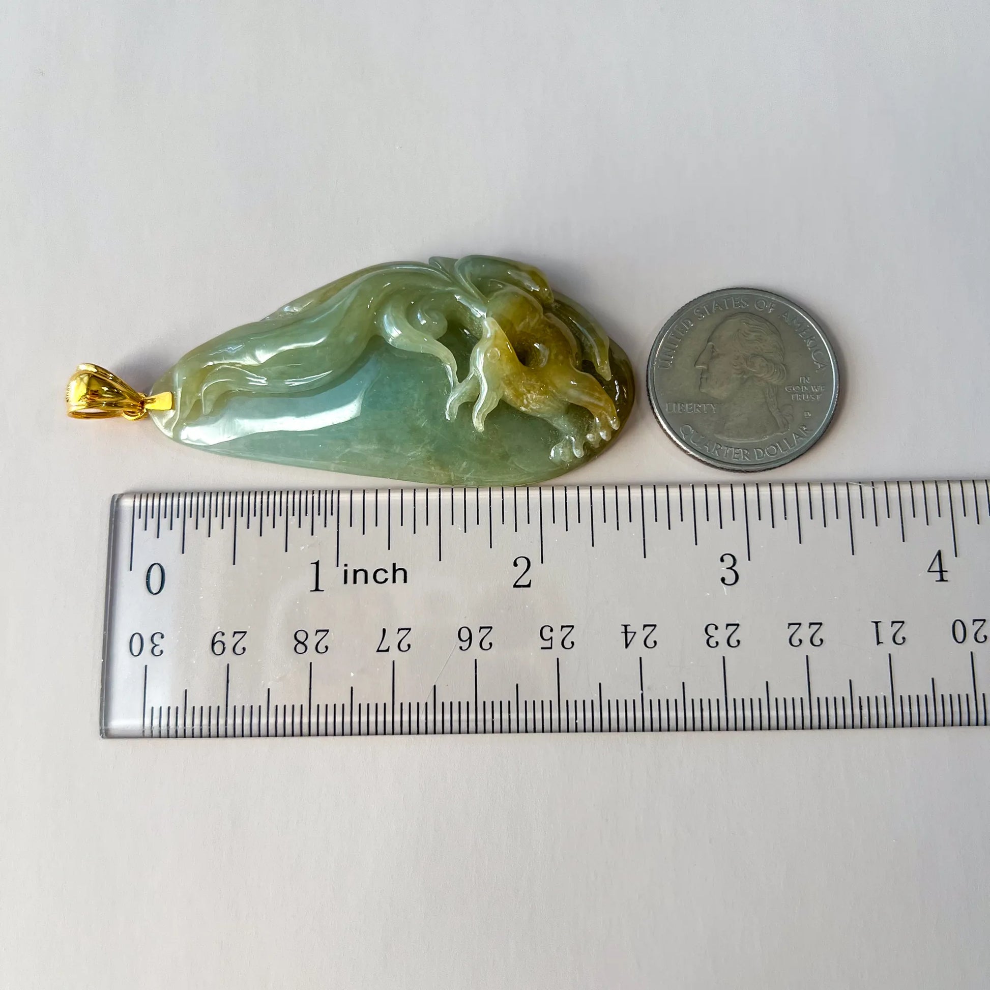Side view showing raised dragon carving, gold-tone bail, ruler scale, and semi-translucent green jade