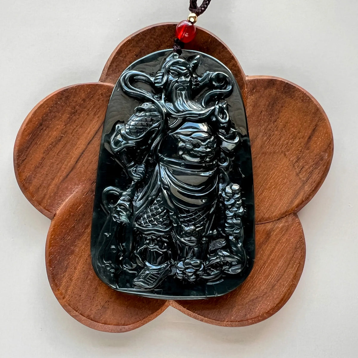 Front view of glossy carved pendant on flower-shaped wood display stand