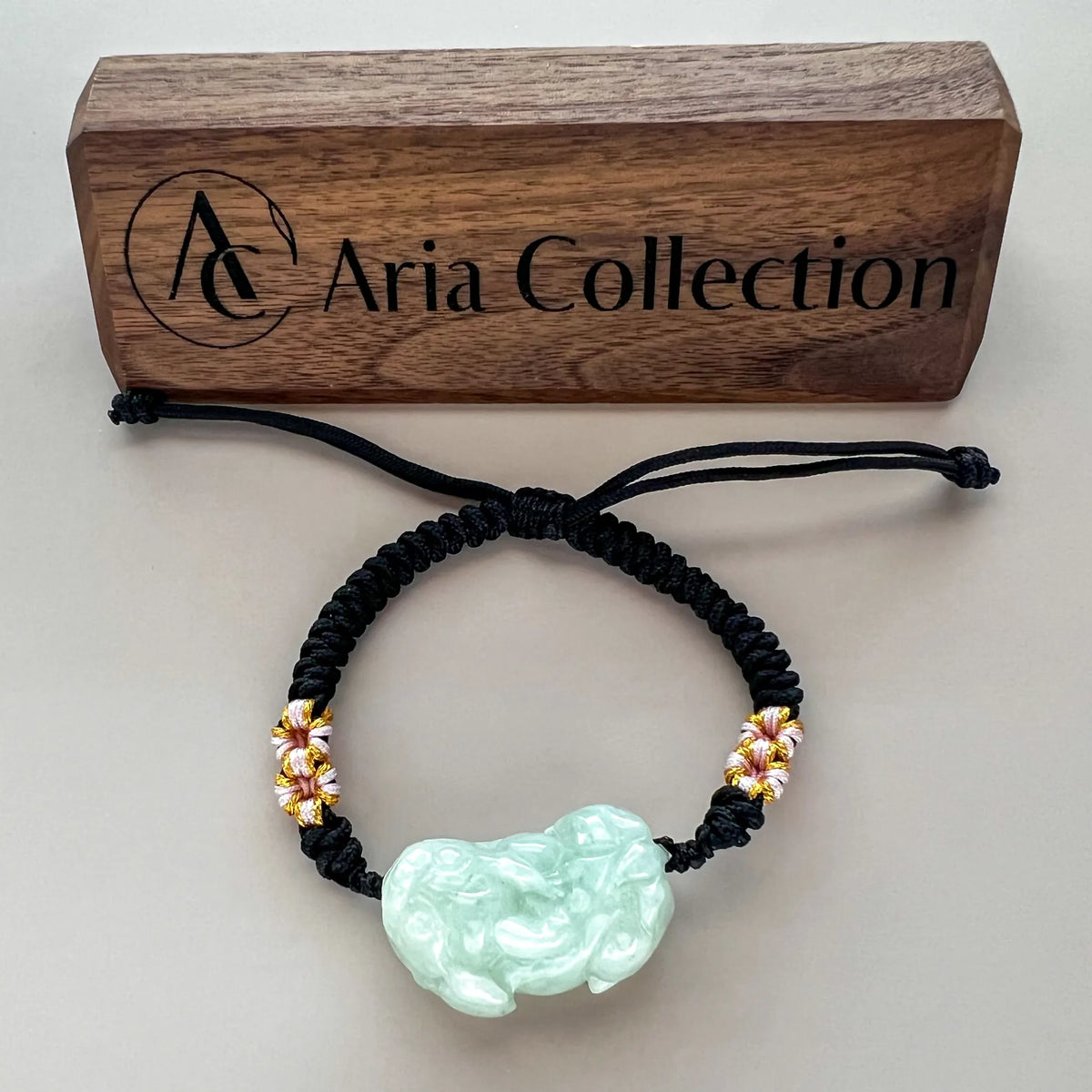 Bracelet laid flat with carved jade center and adjustable black cord, studio view