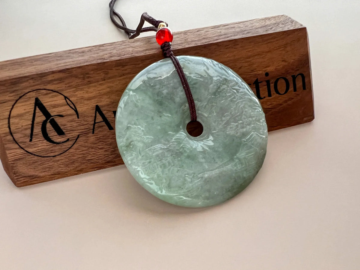 Side-angled view of glossy carved jade pendant on branded wood plaque, showing depth and cord detail