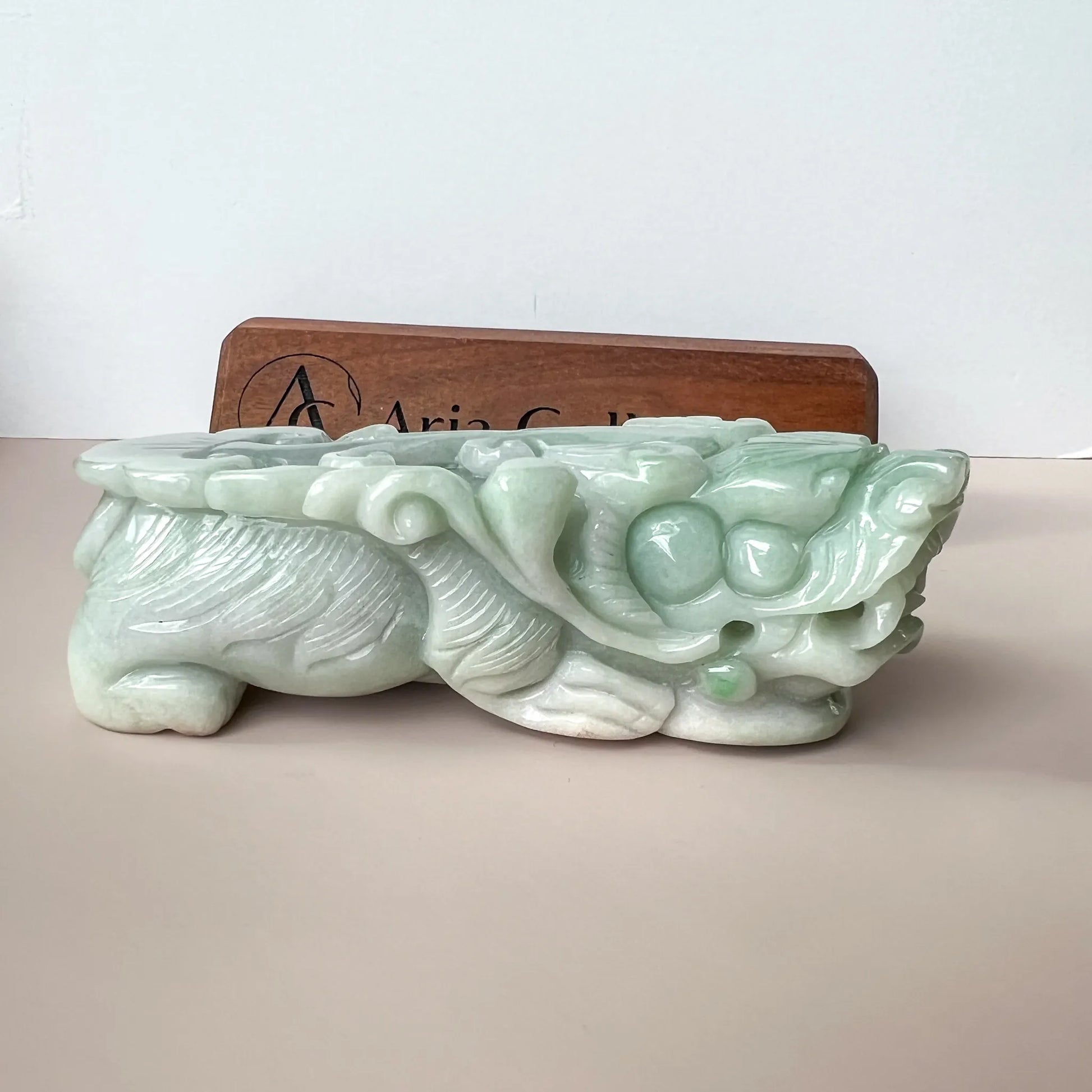 Side view of carved pale green jade sculpture with glossy polished finish on display