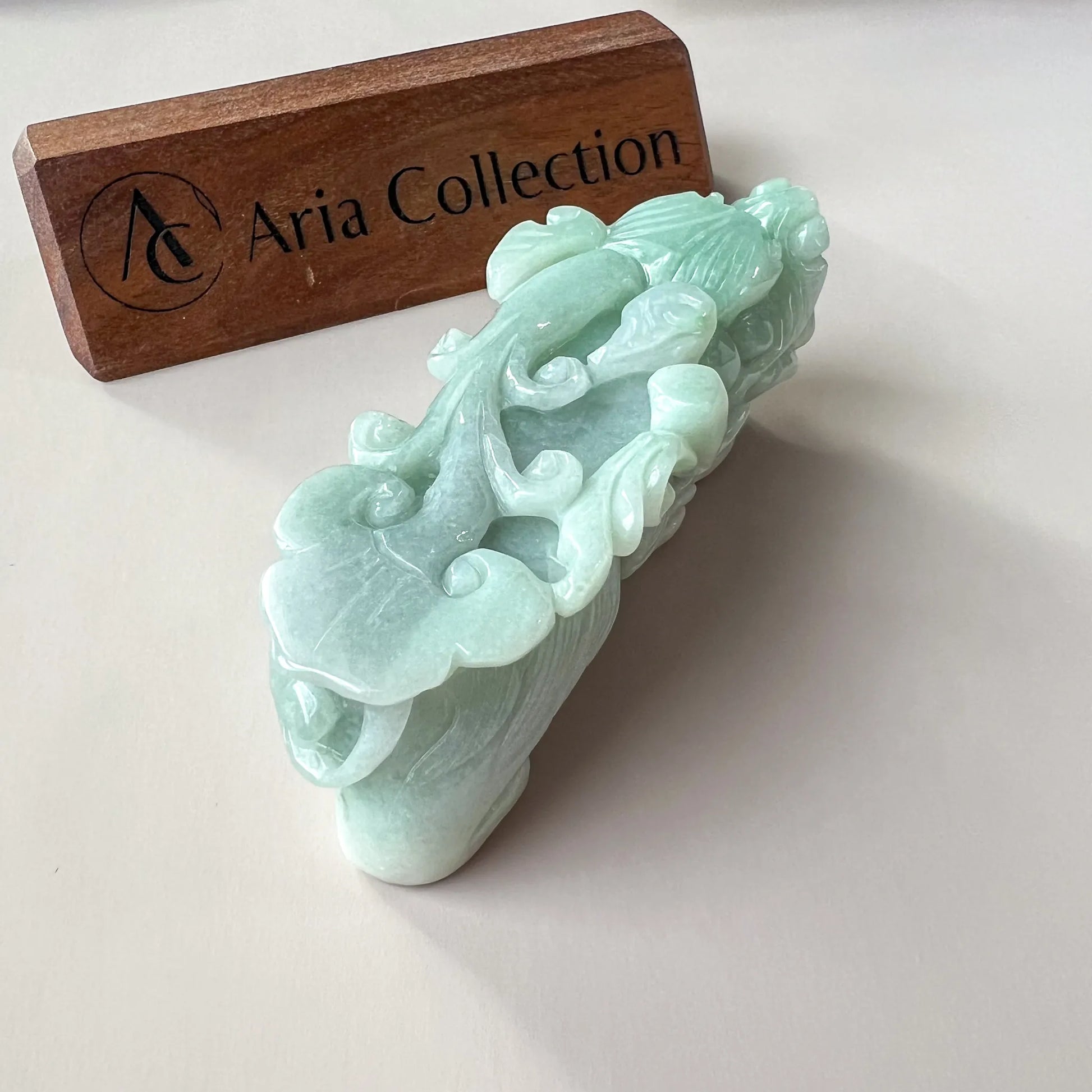 Angled rear view of pale green jade carving with high-gloss finish on white background