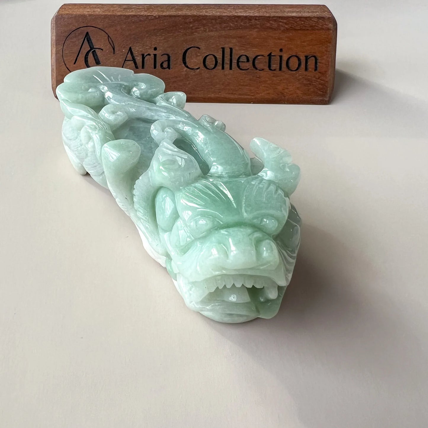 Front angled view of hand-carved pale green jade sculpture with detailed relief work