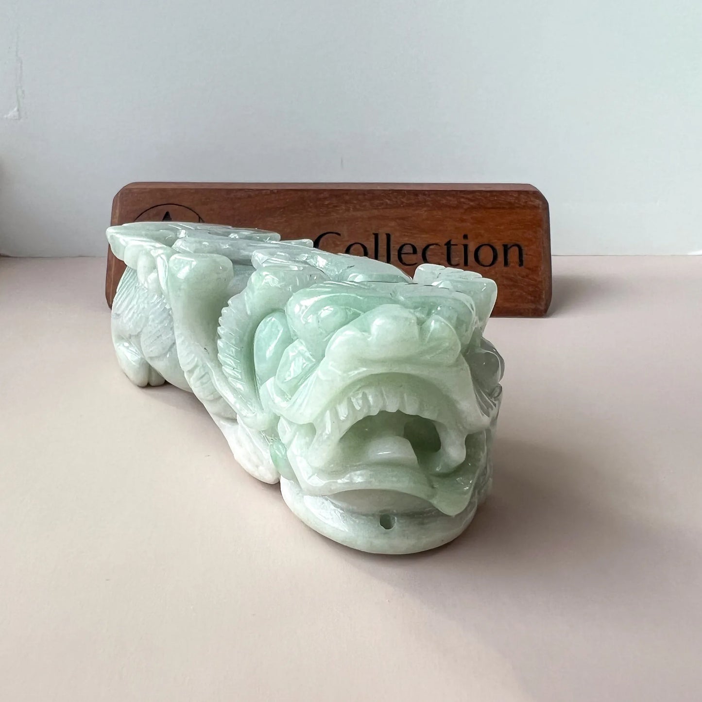Close front view of pale green jade carving showing open mouth and polished contours