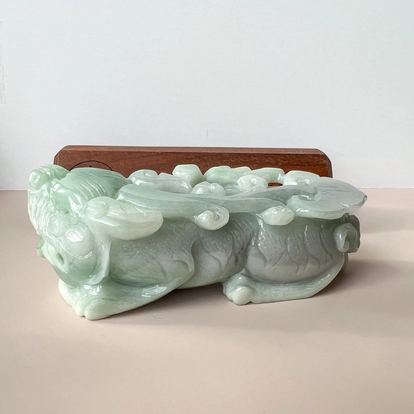 Side profile of glossy pale green jade sculpture with layered carved details