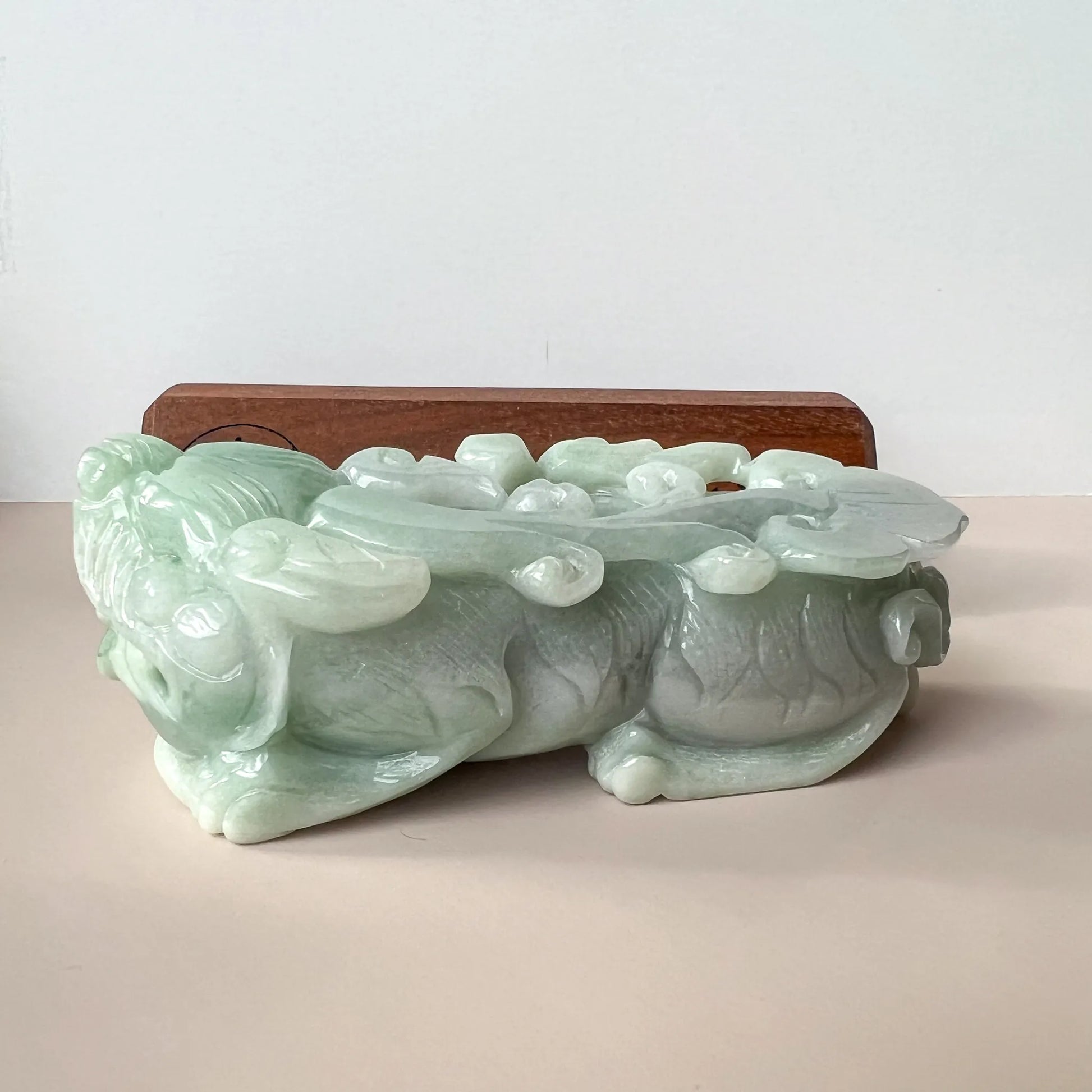 Side profile of glossy pale green jade sculpture with layered carved details