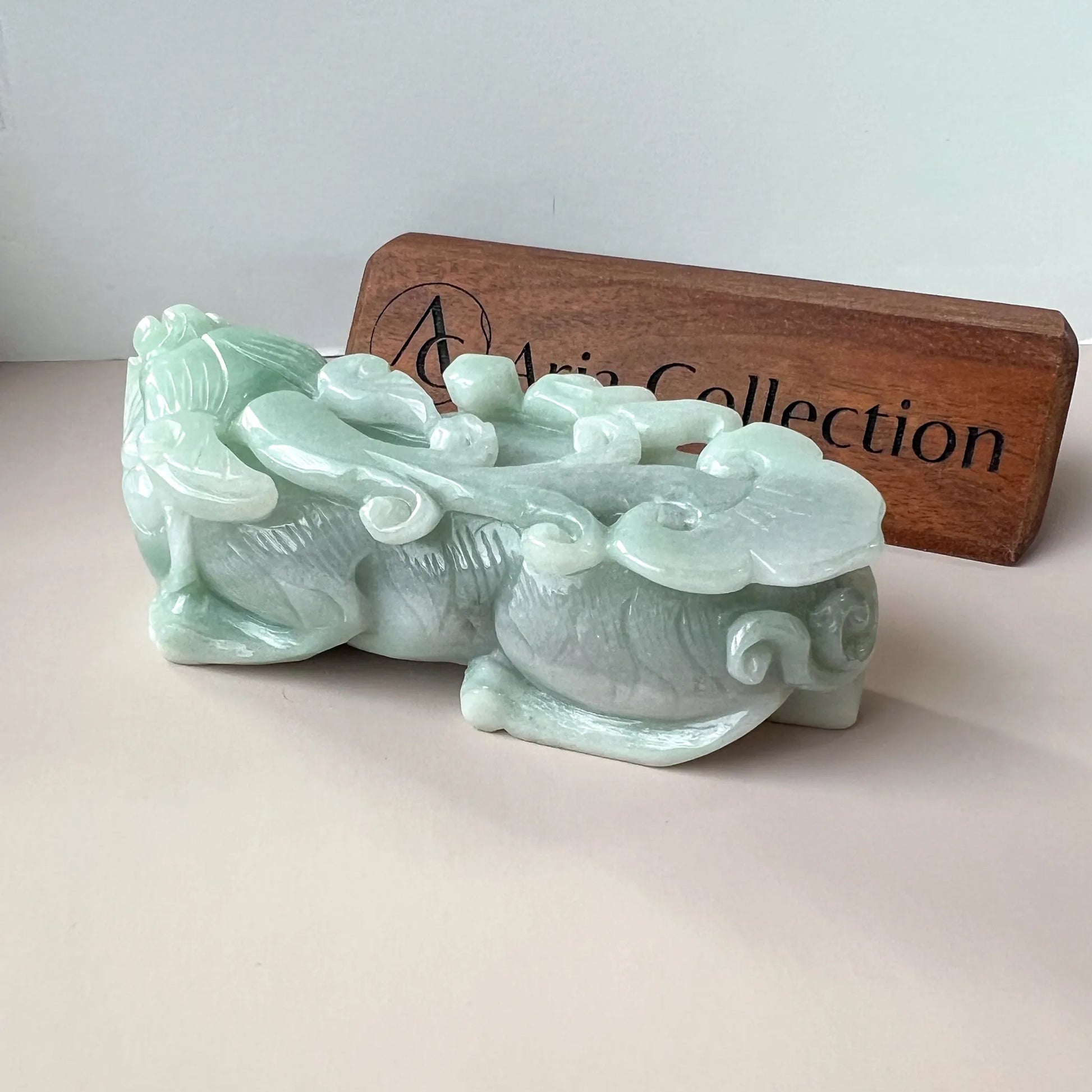 Rear angled view of polished pale green jade carving with flowing ornamental details