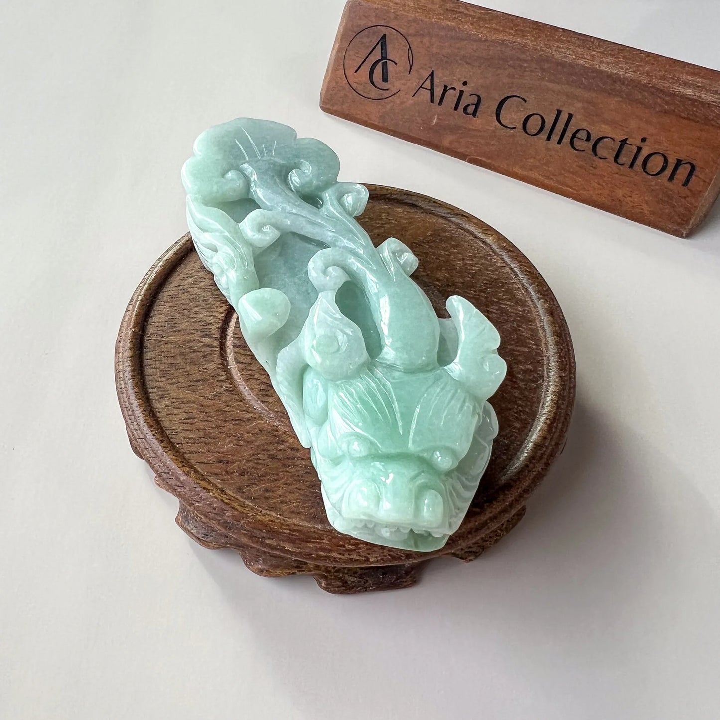 Side view of light green polished dragon carving on round wooden display stand
